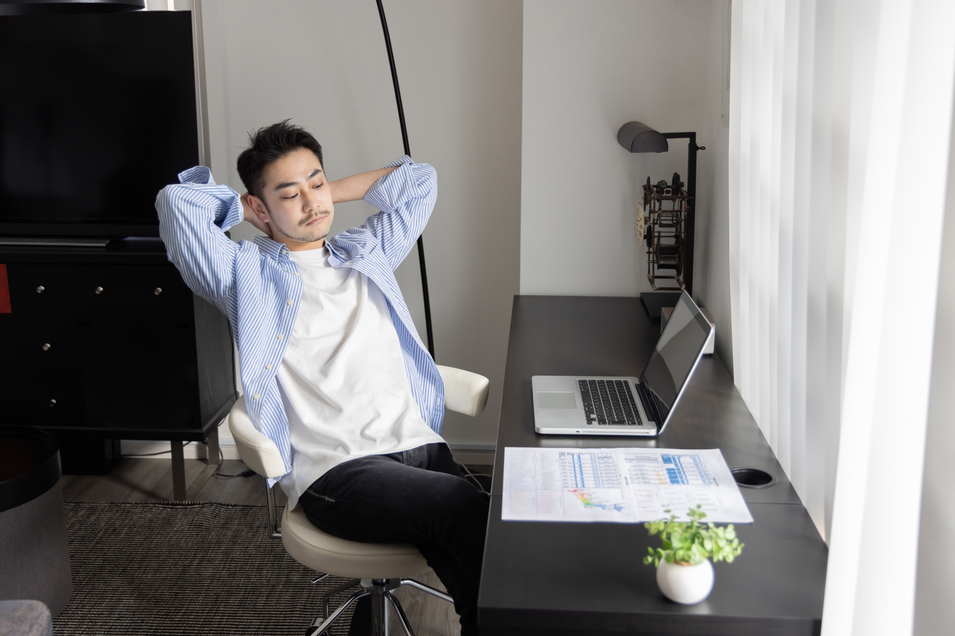 椅子に座って両手を頭の後ろで組む男性