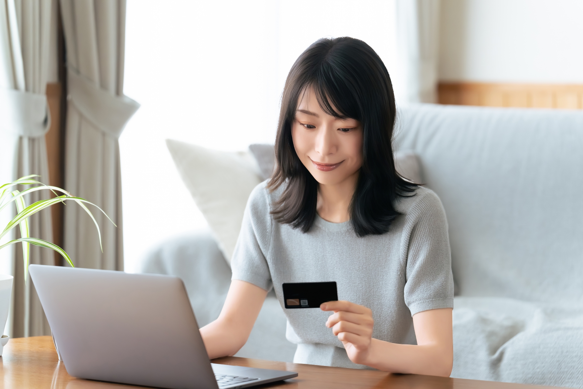 パソコンの前でクレジットカードを見る女性