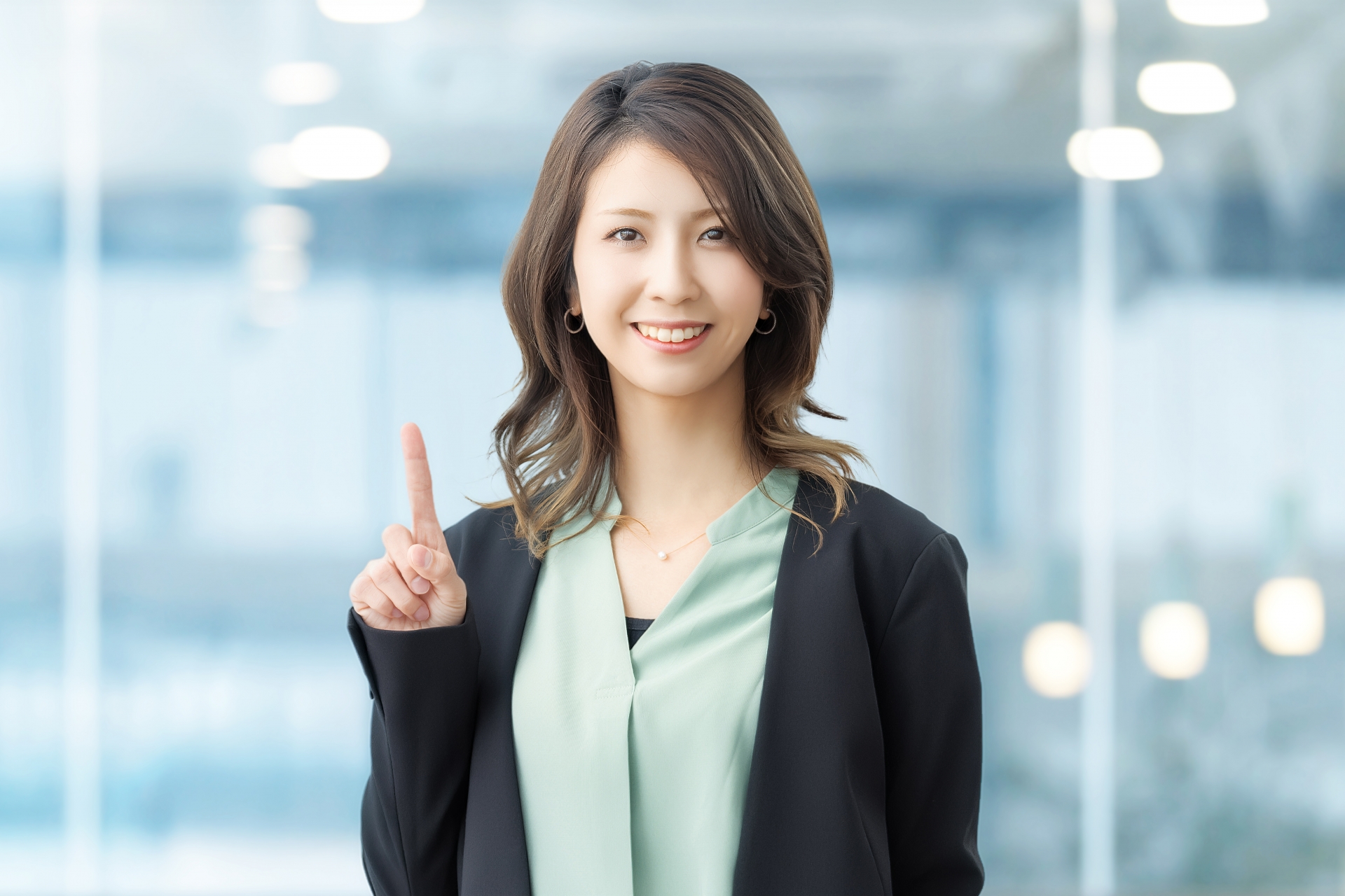 人差し指を立てて案内する笑顔の女性