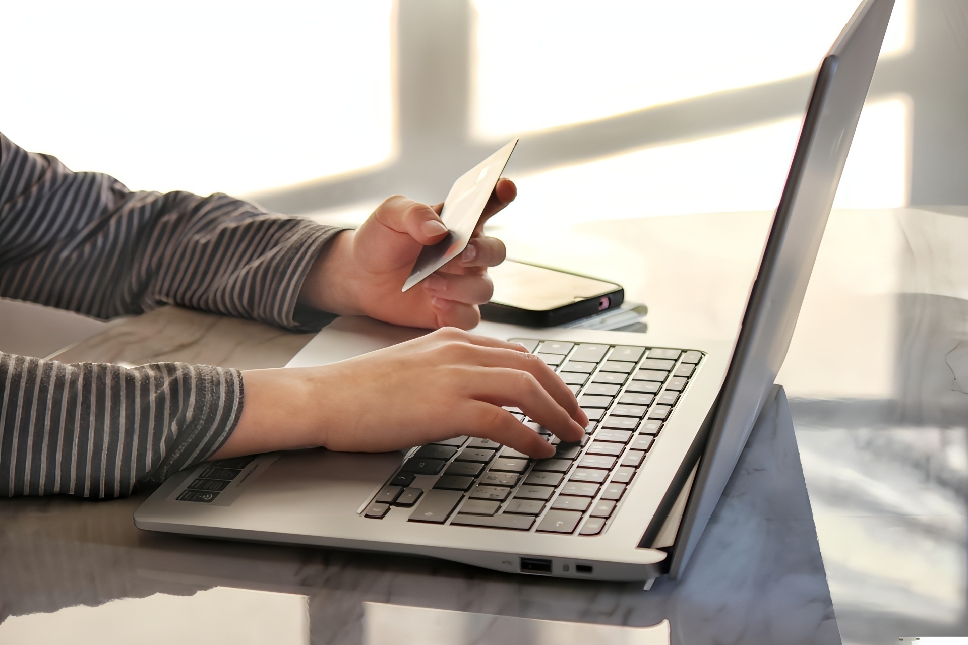 クレジットカードを見ながらパソコンを操作する人