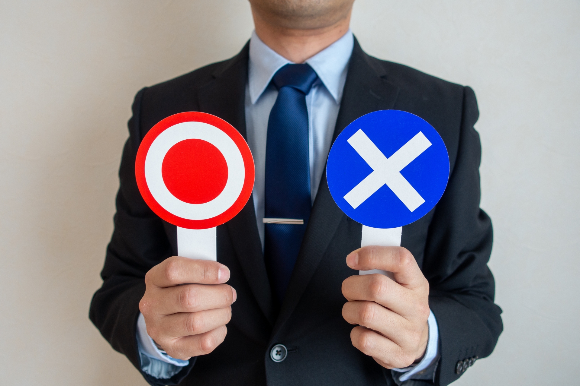 丸バツの札を持つ人