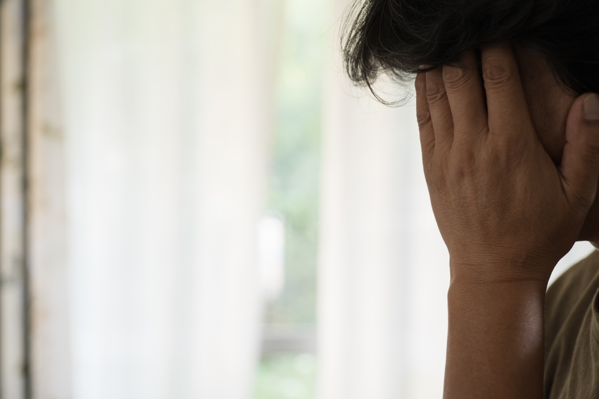 顔を覆って悩んでいる中年男性