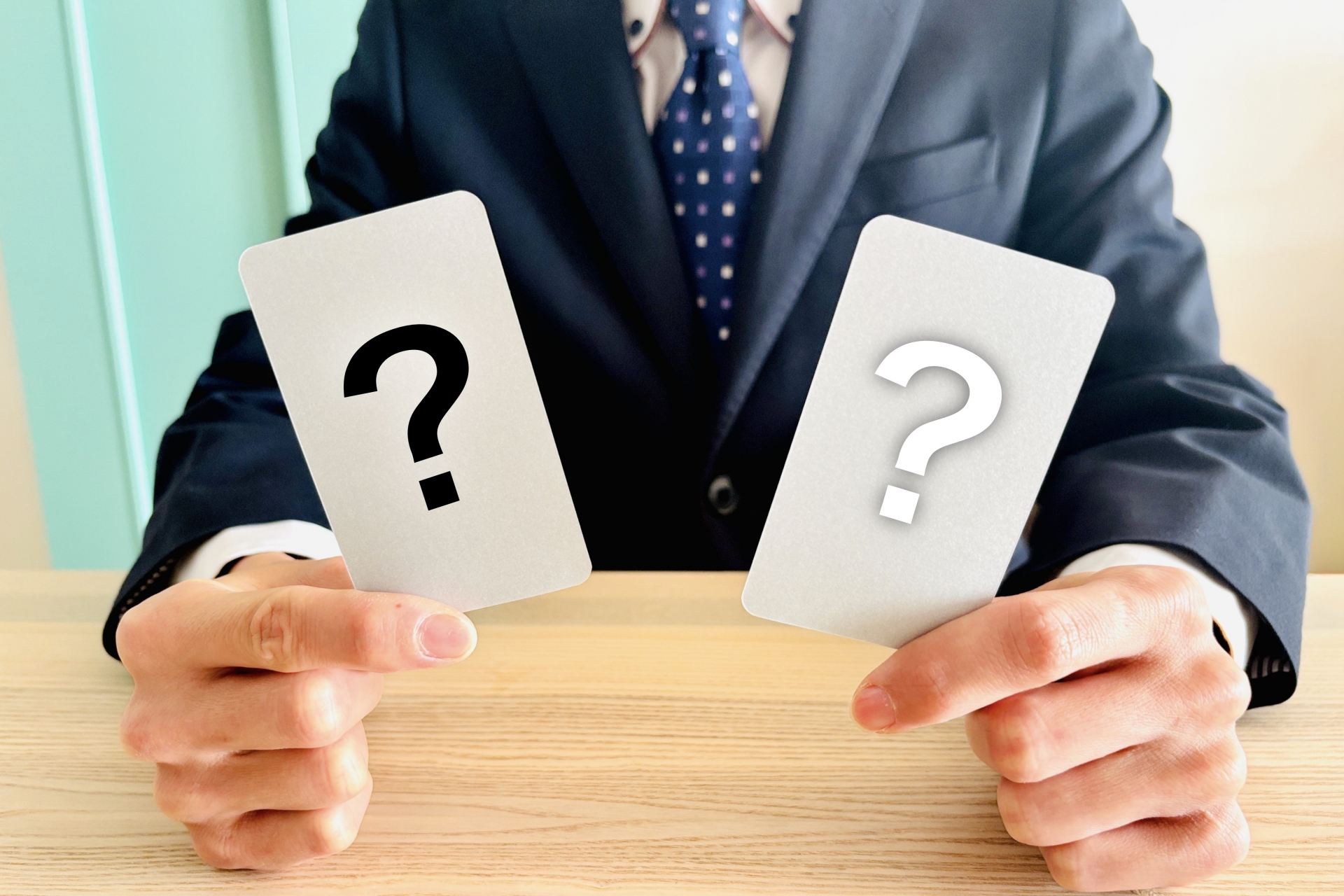 両手にハテナのカードを持つ人