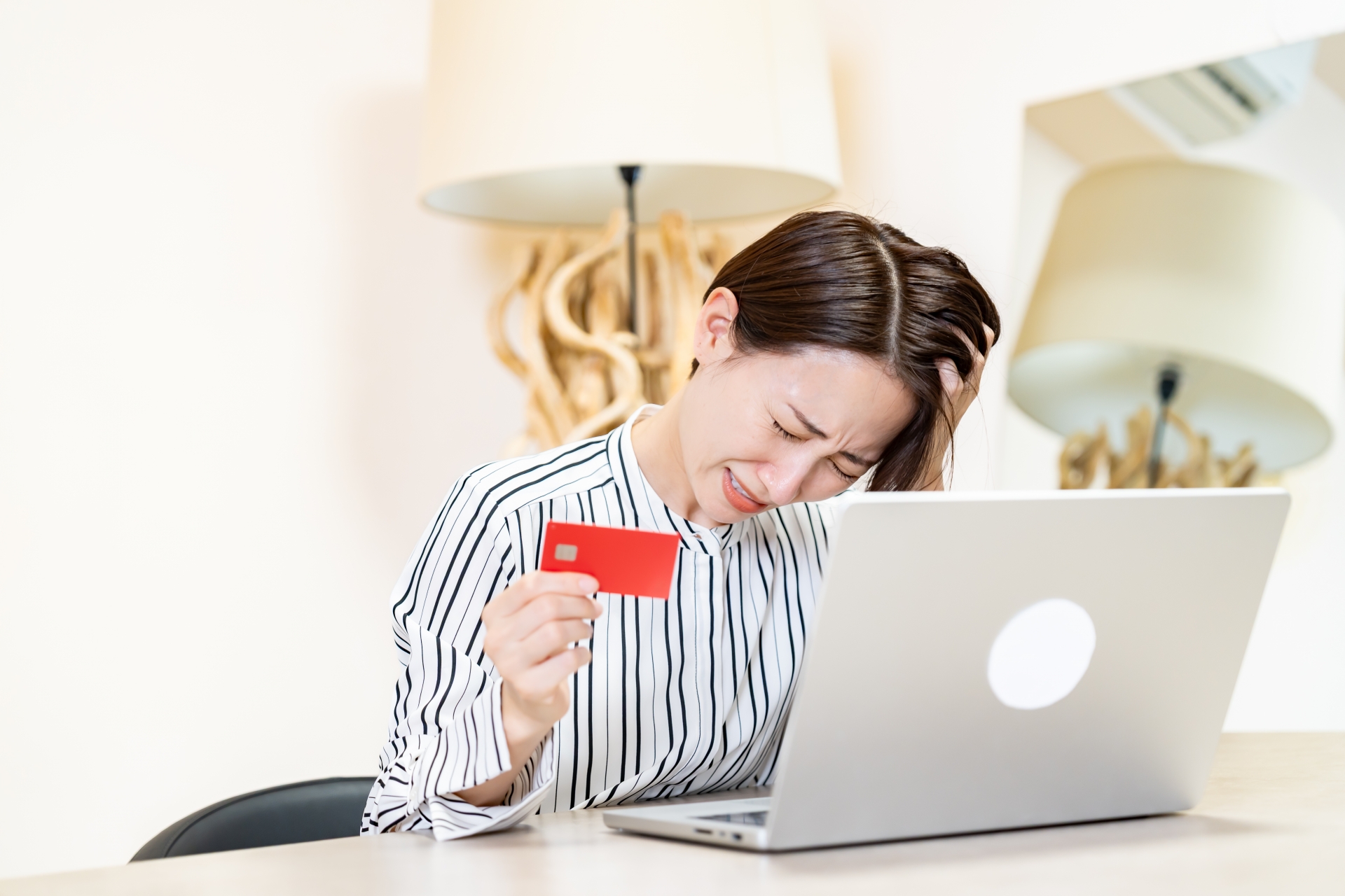 パソコンの前でクレジットカードを持って頭を抱える人