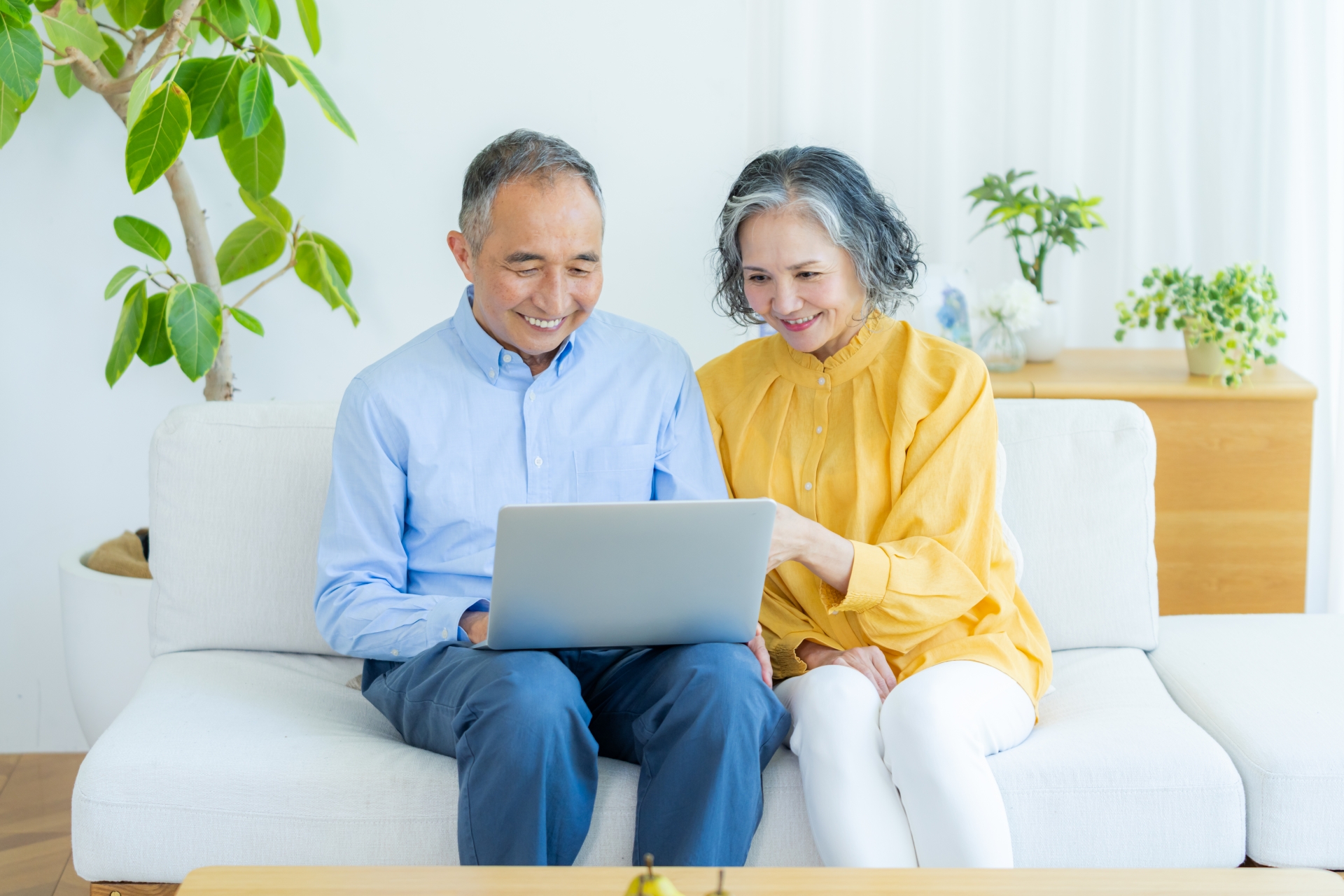 ソファに座ってパソコンを見る夫婦