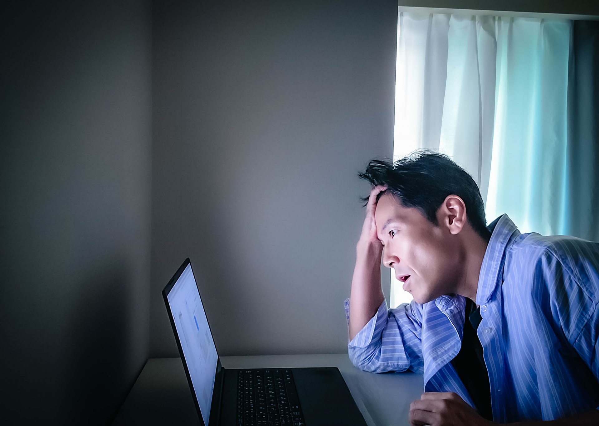 暗い部屋で悩んでる男性
