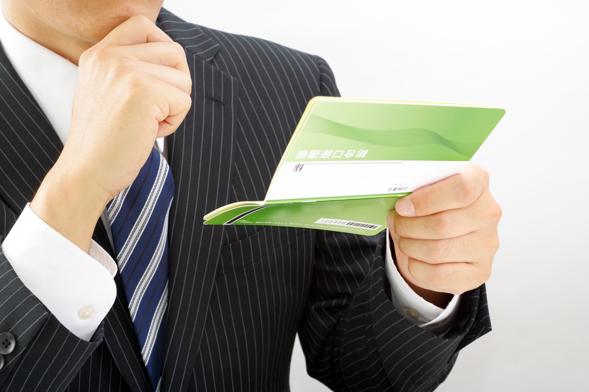 顎に手を当てて通帳を見る人