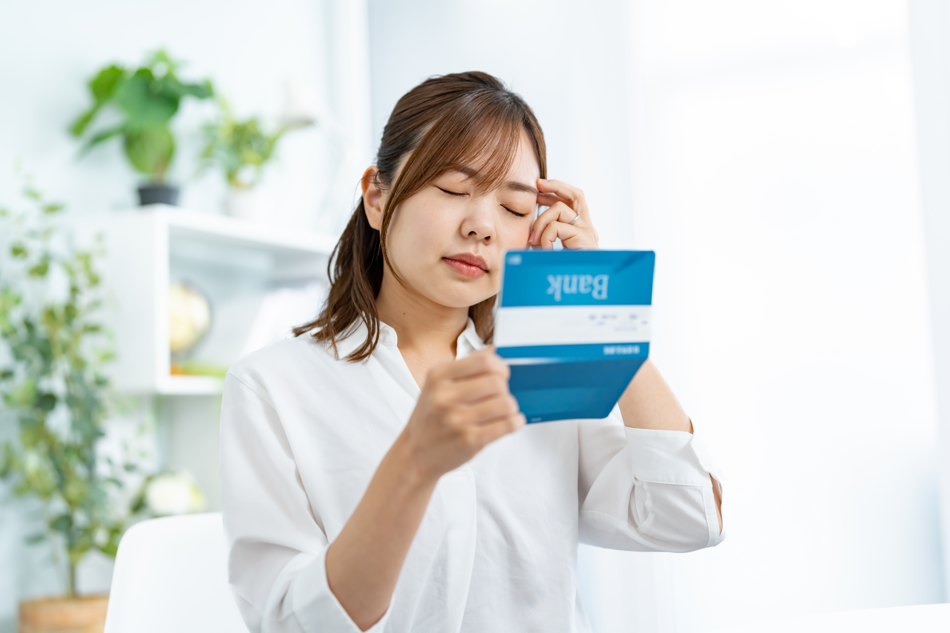 通帳を見て頭を抱える女性