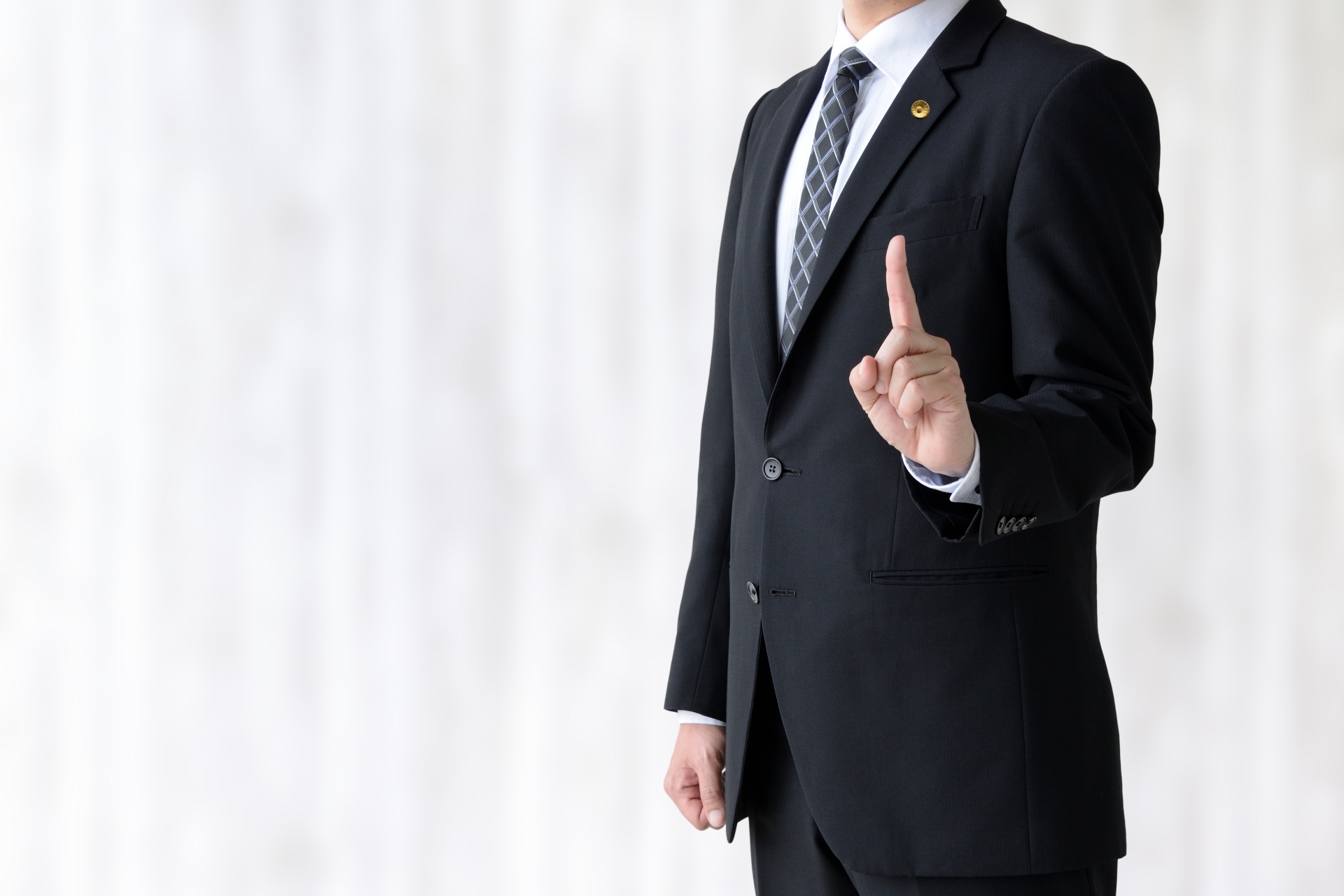 人差し指を立てるスーツの男性