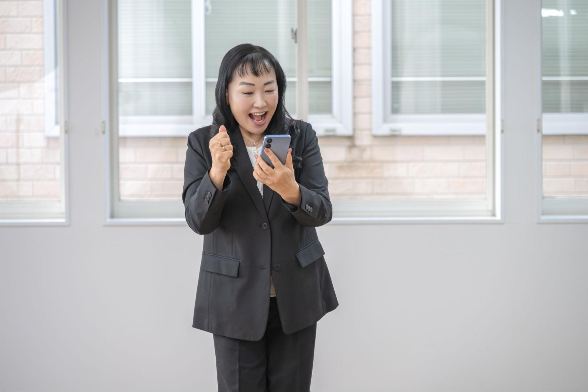 スマホを見て喜ぶビジネスウーマン
