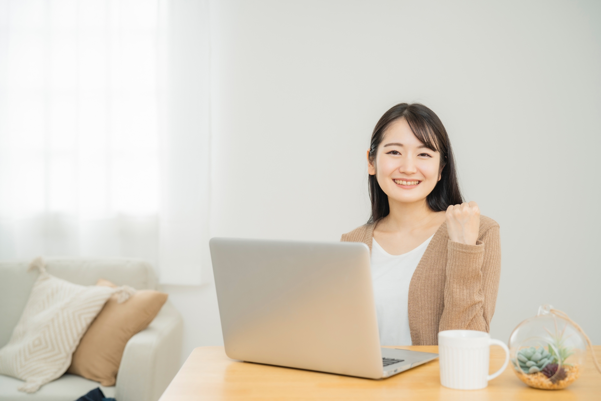 家でノートパソコンを使う女性（ガッツポーズ）