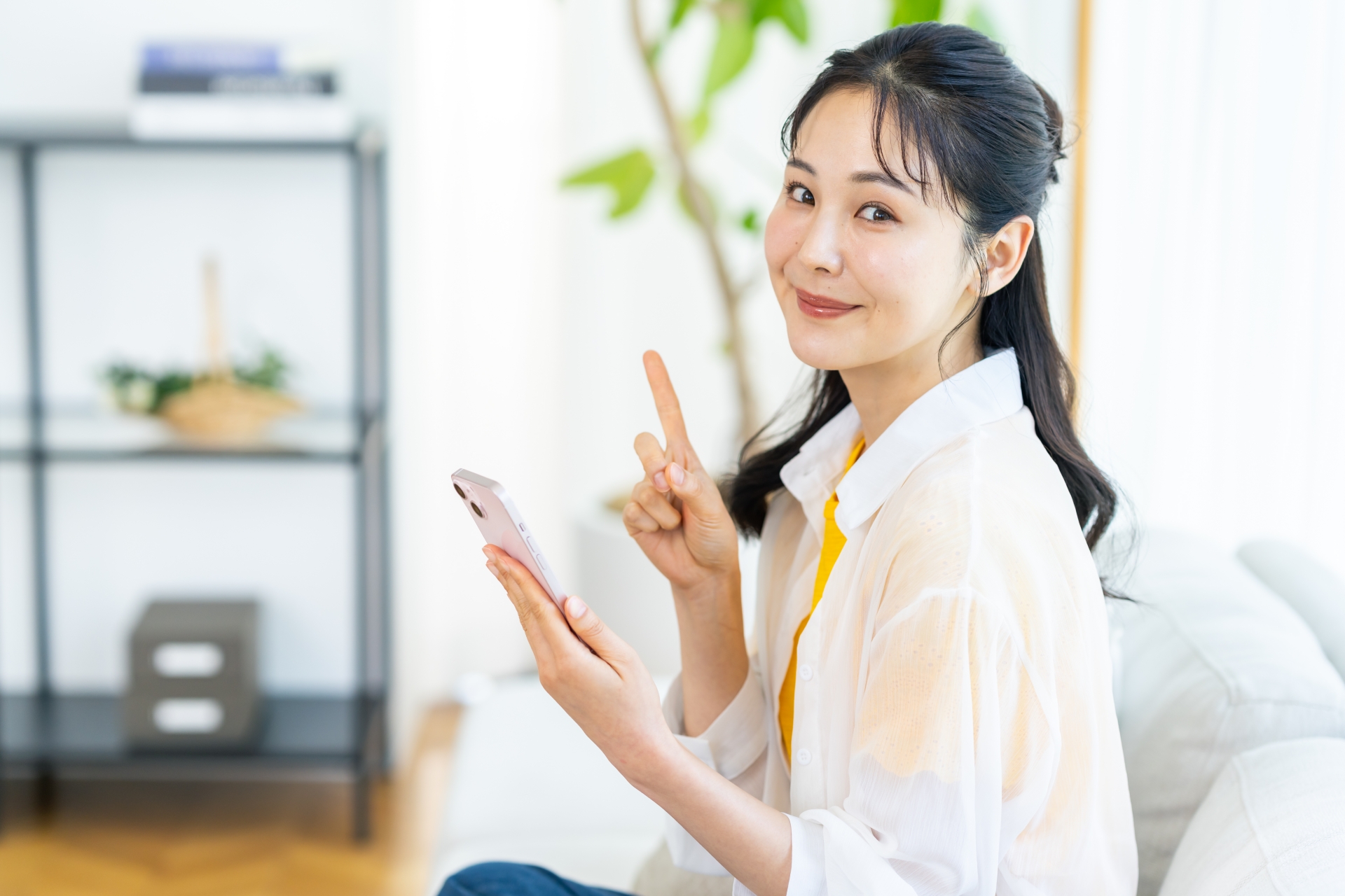 部屋でスマホを操作する女性