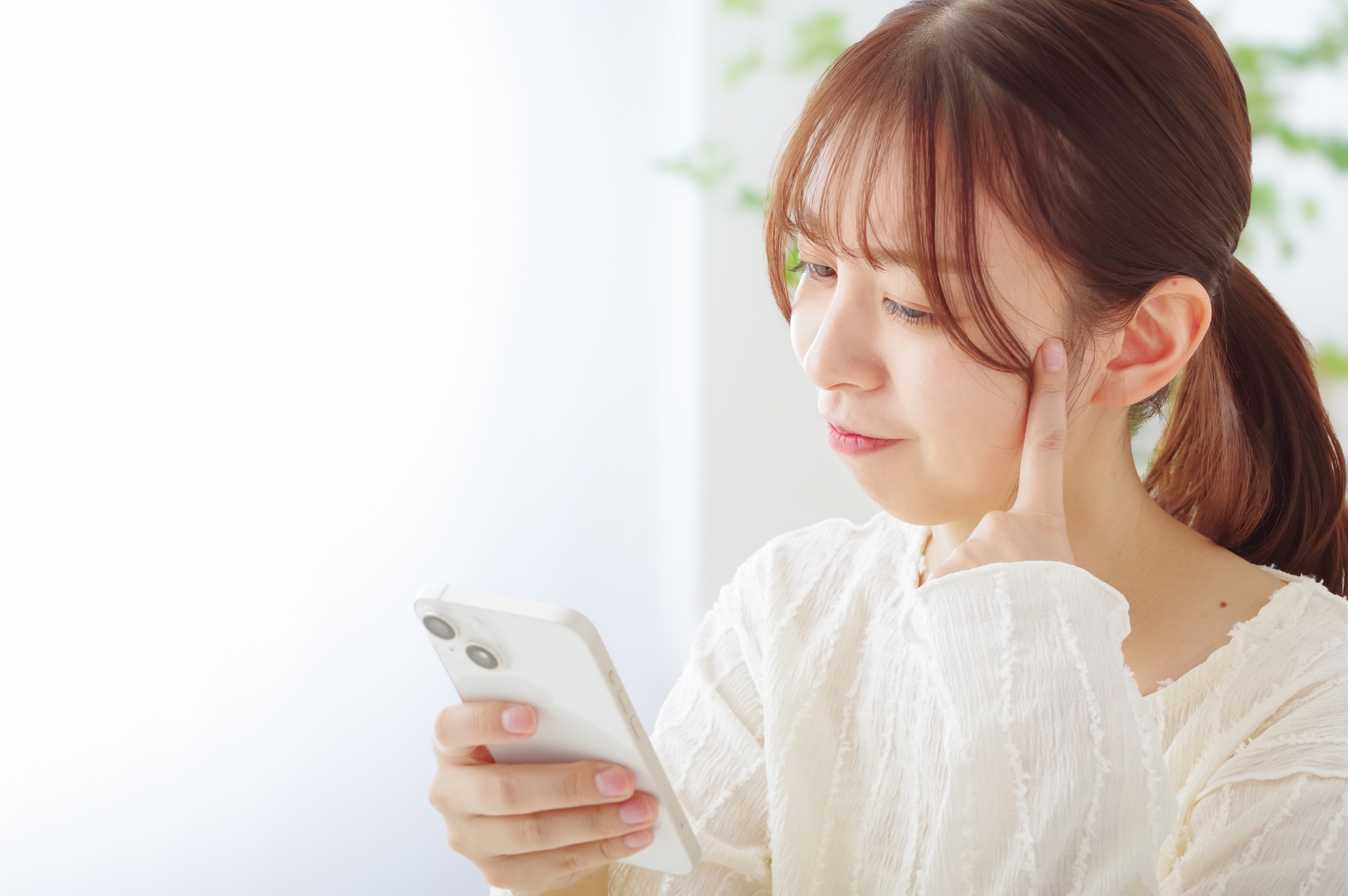 スマホを見て悩む女性