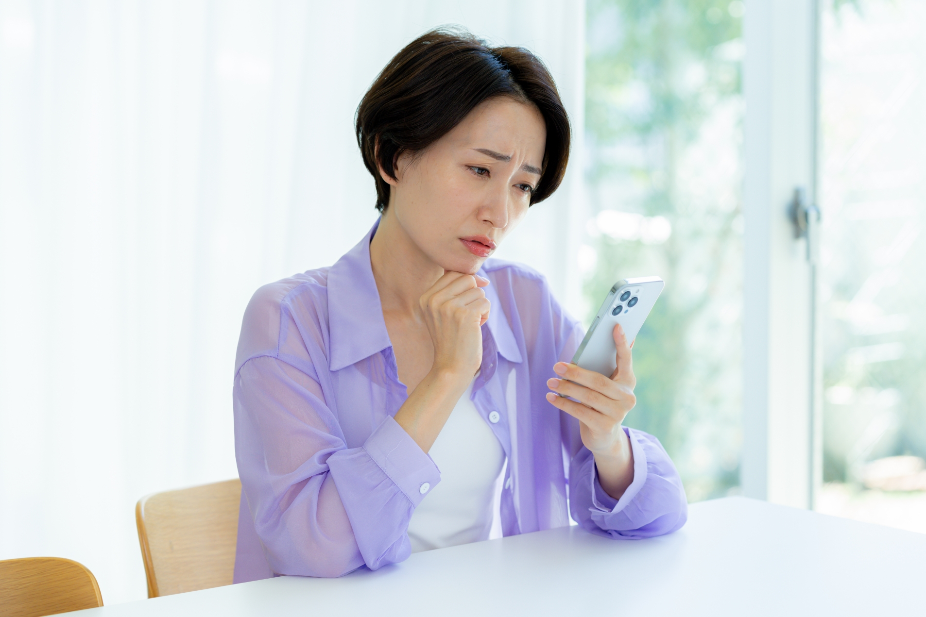 スマホを見て悩む女性
