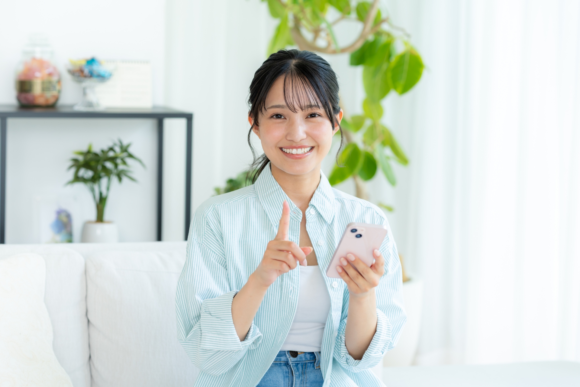 部屋でスマホを操作する若い女性