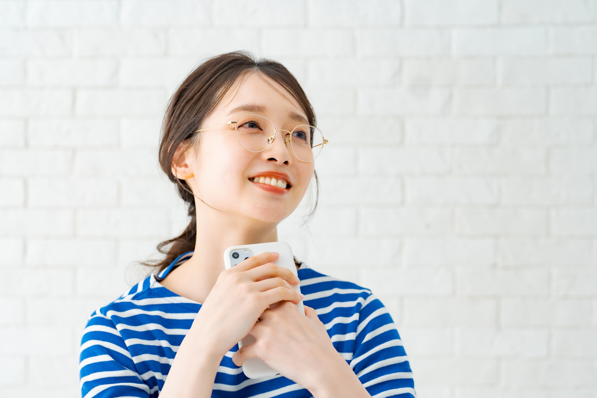 スマートフォンを手に笑顔のメガネ女子