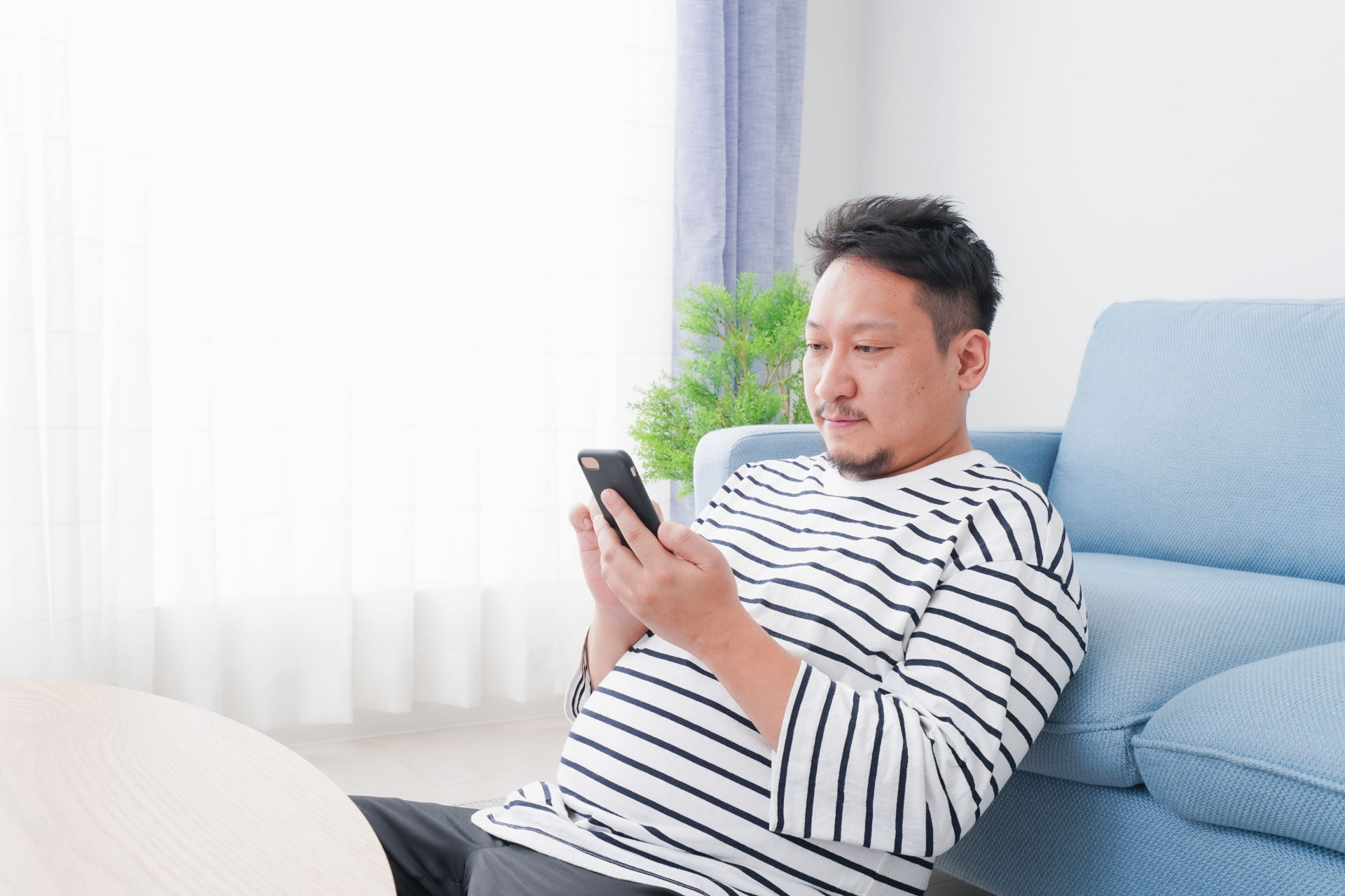 部屋でスマホを使う男性