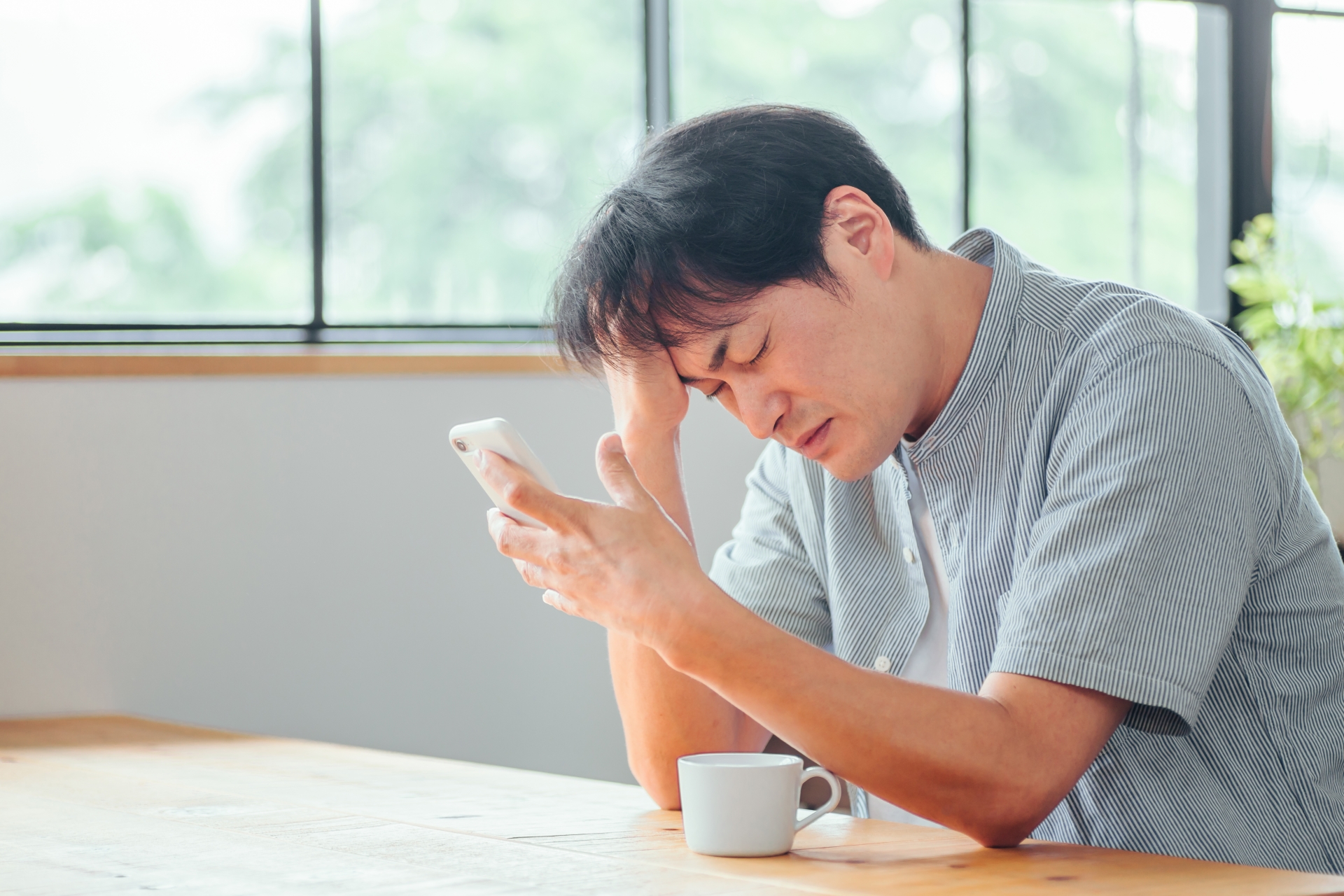 スマホを見て悩む男性