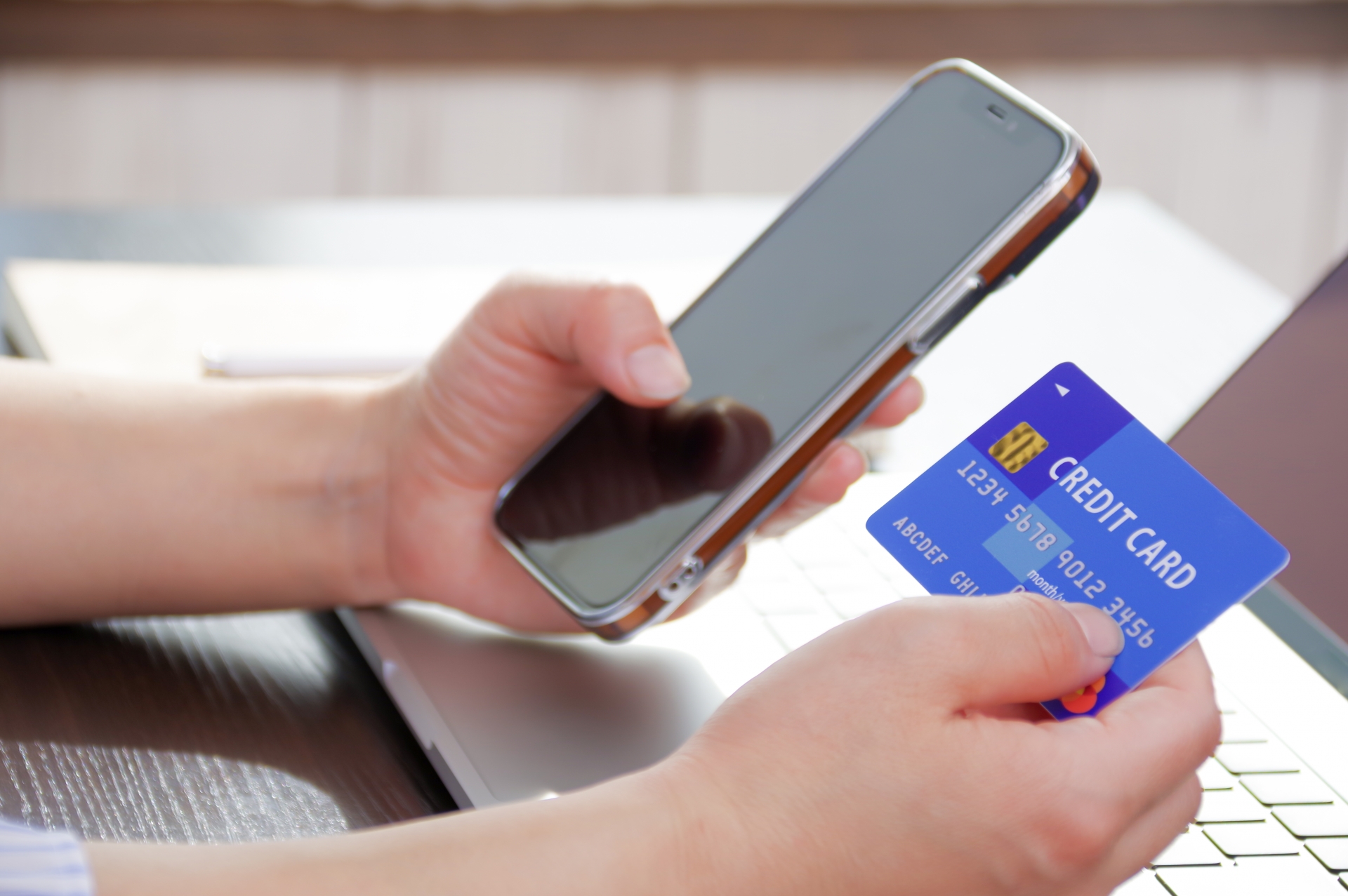 スマホとクレジットカードを持つ女性