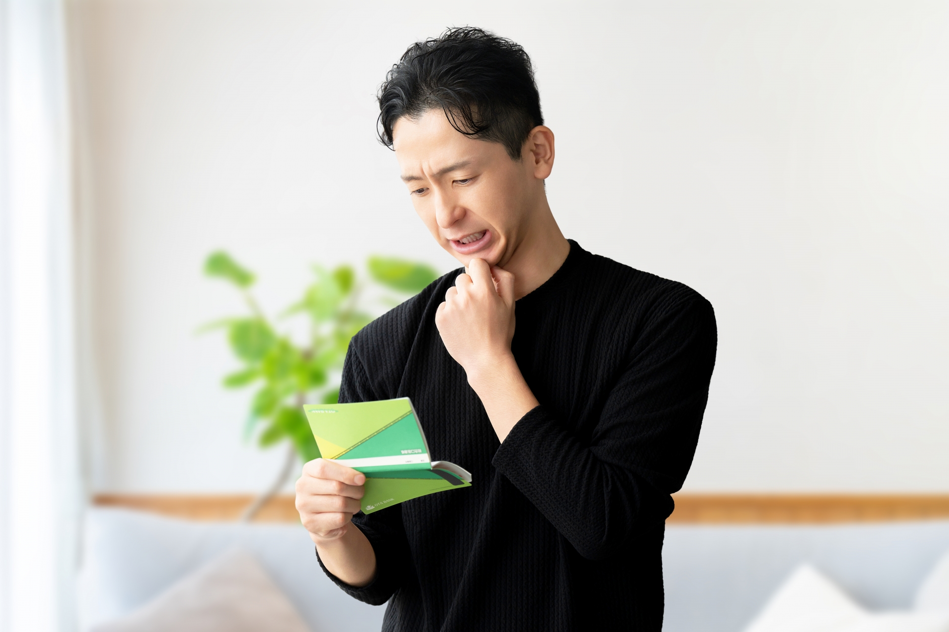 通帳を見て悩む男性