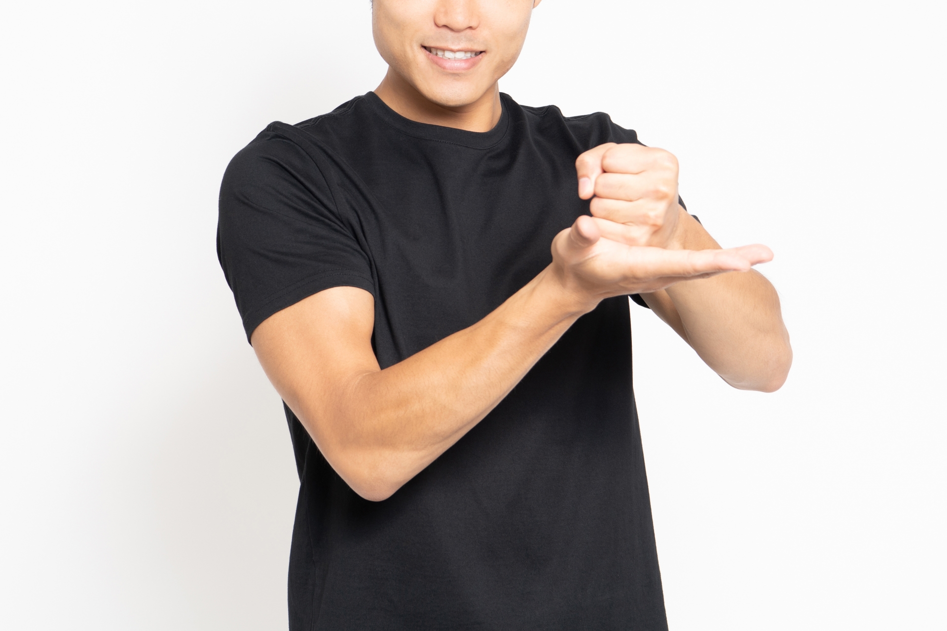 白い背景の前に立って納得したポーズをする黒いTシャツを着ている男性