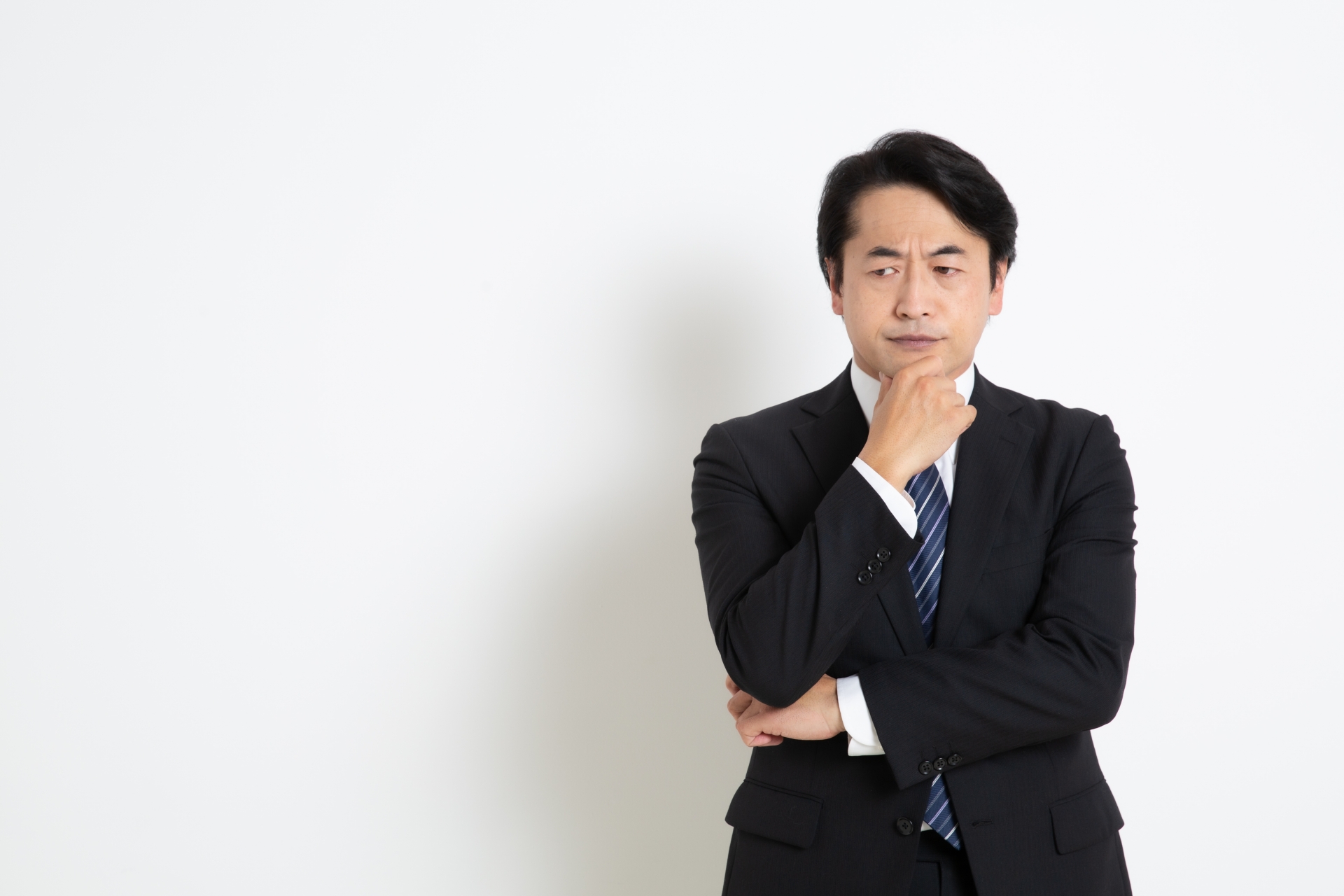 アゴに手をあて悩んでいる中年のサラリーマン男性