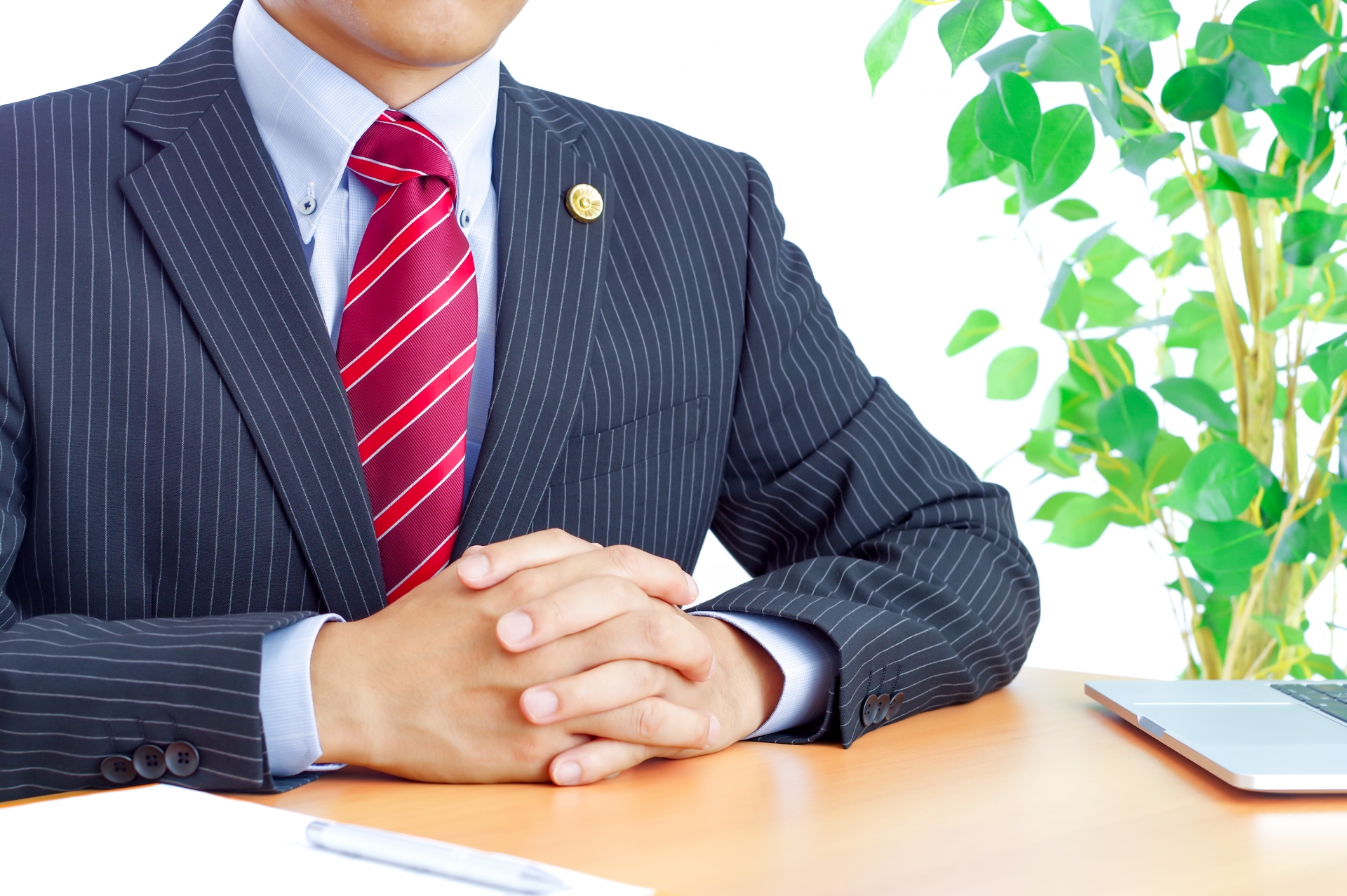 手を組み相談を聞く男性弁護士