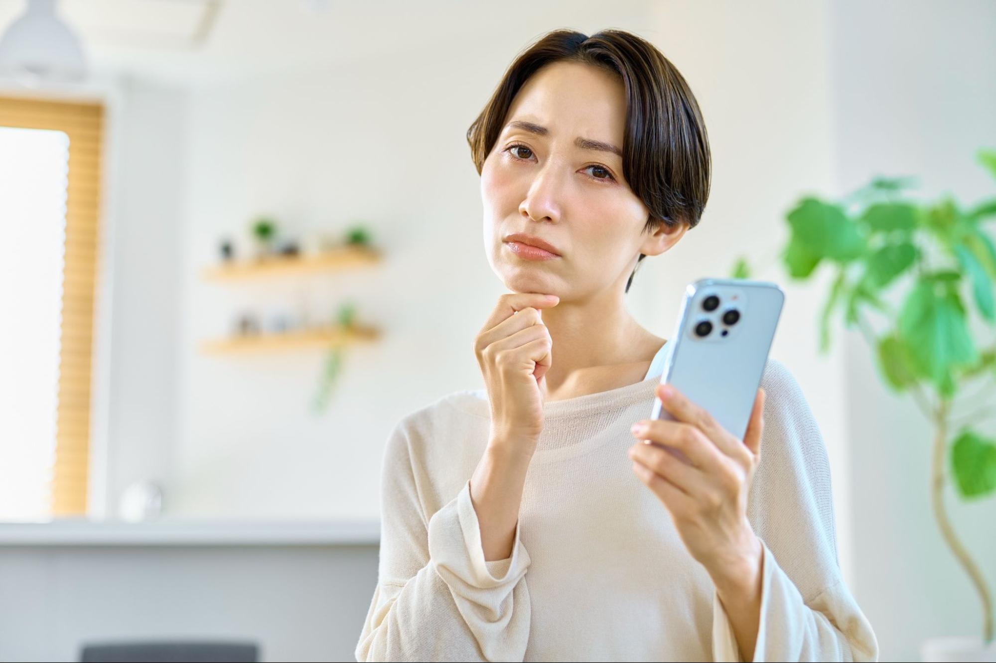 スマホを見て悩む女性