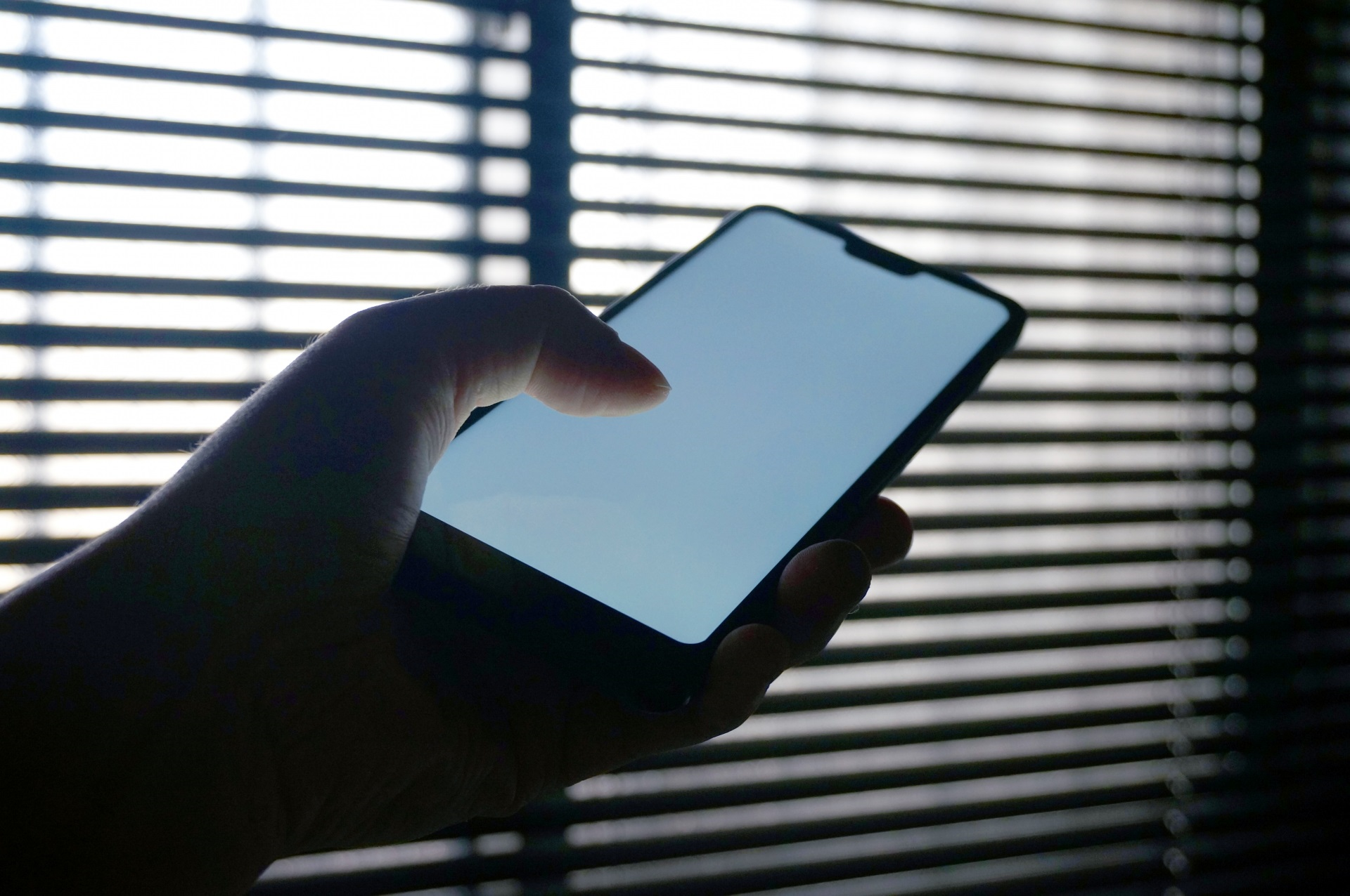 昼間の窓際の室内でスマホを見る