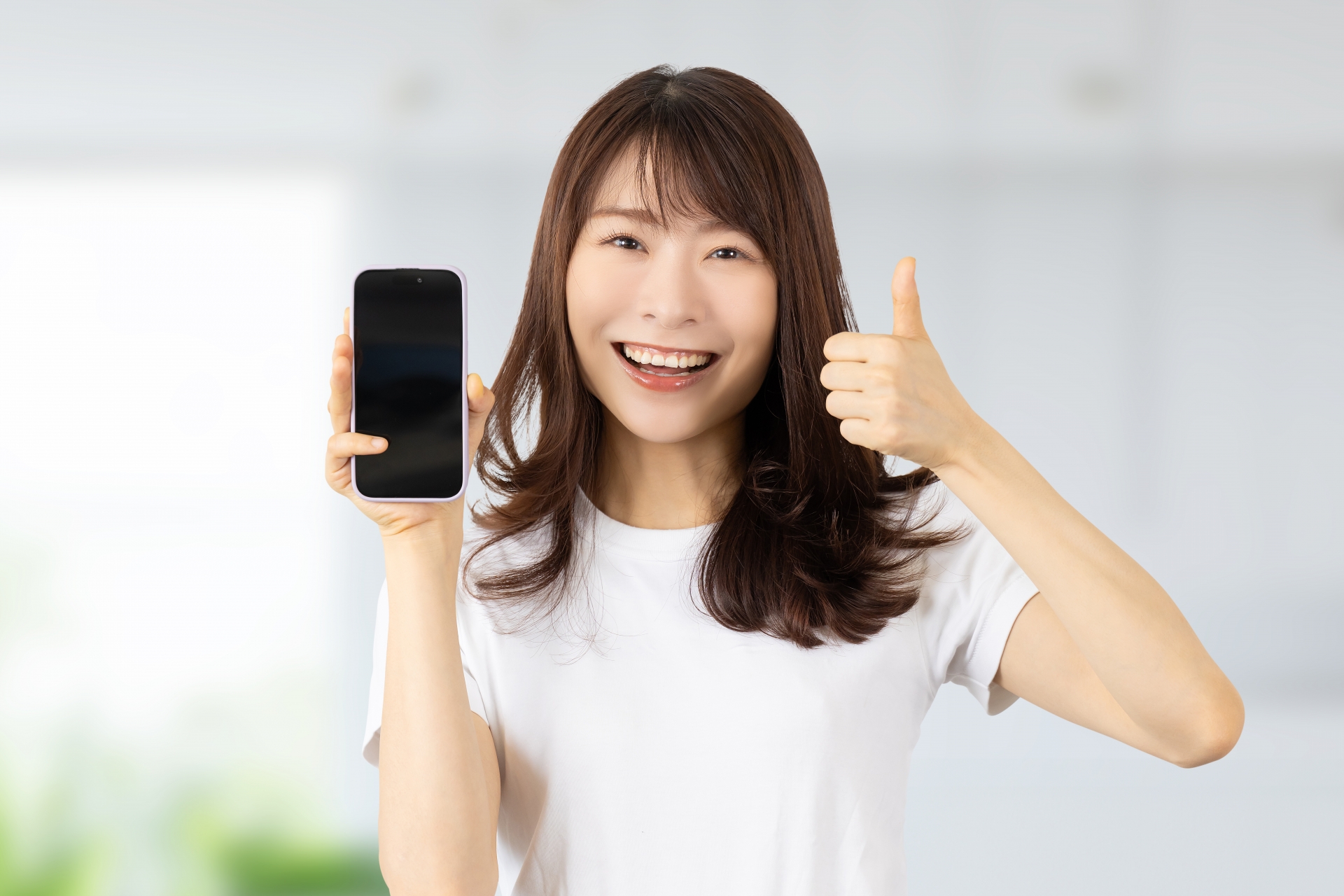 スマホを持っていいね！のポーズをする女性