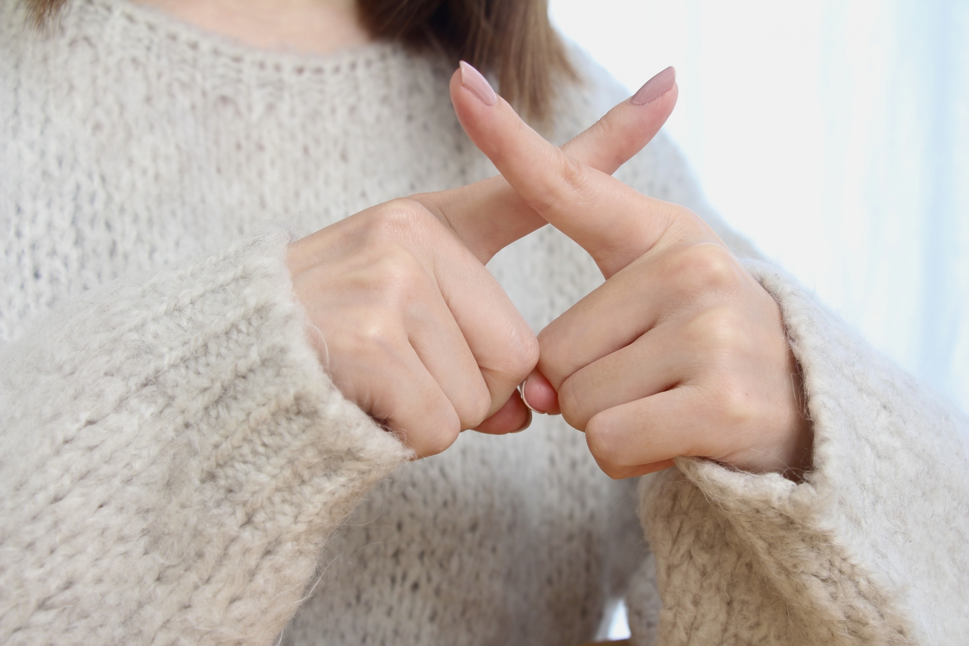 バツポーズの女性の手元