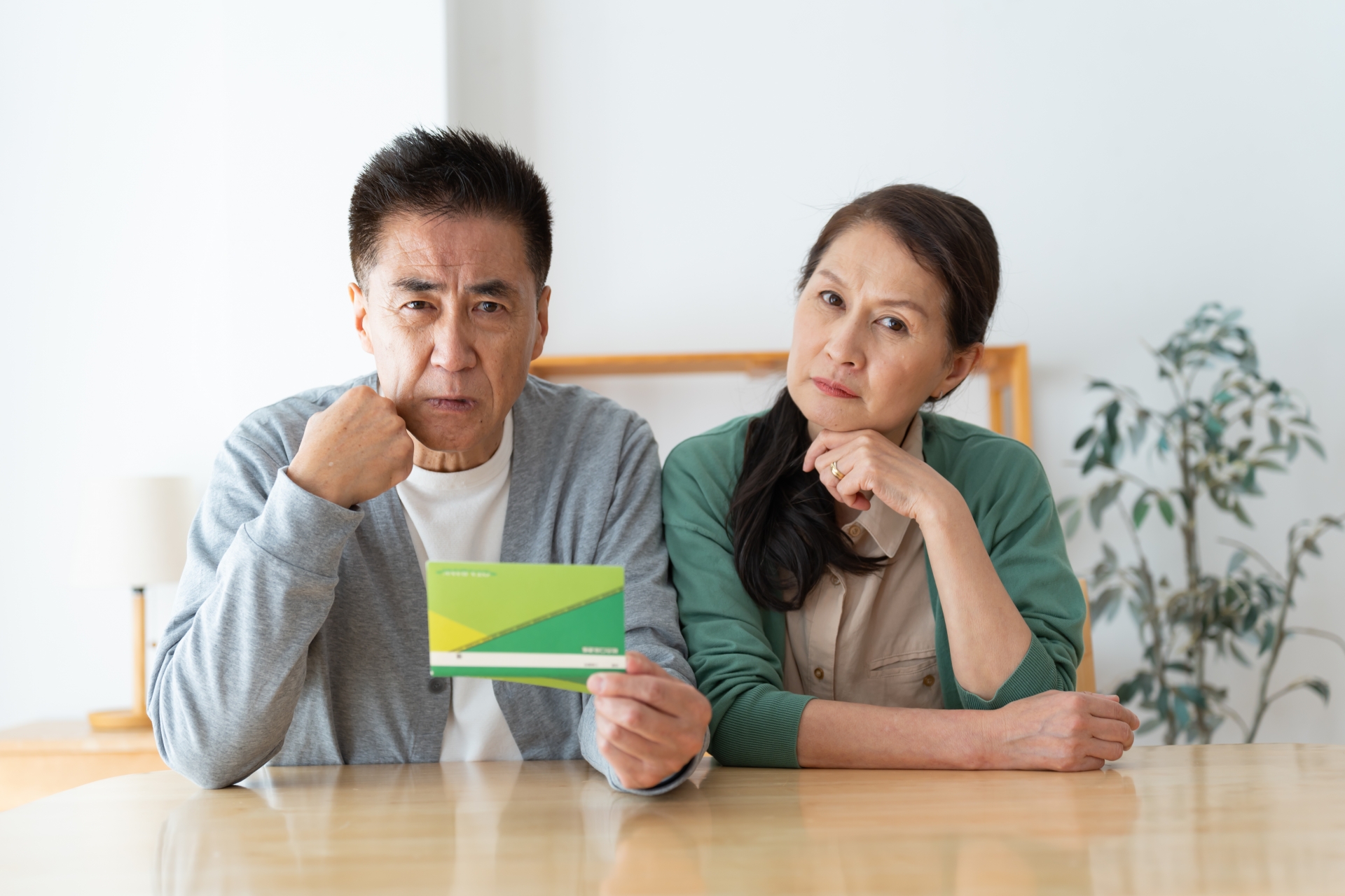 通帳を持ち頭をかしげる夫婦