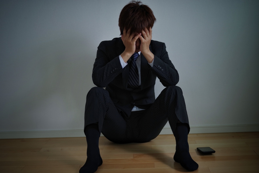 床に座り込み顔を隠す男性