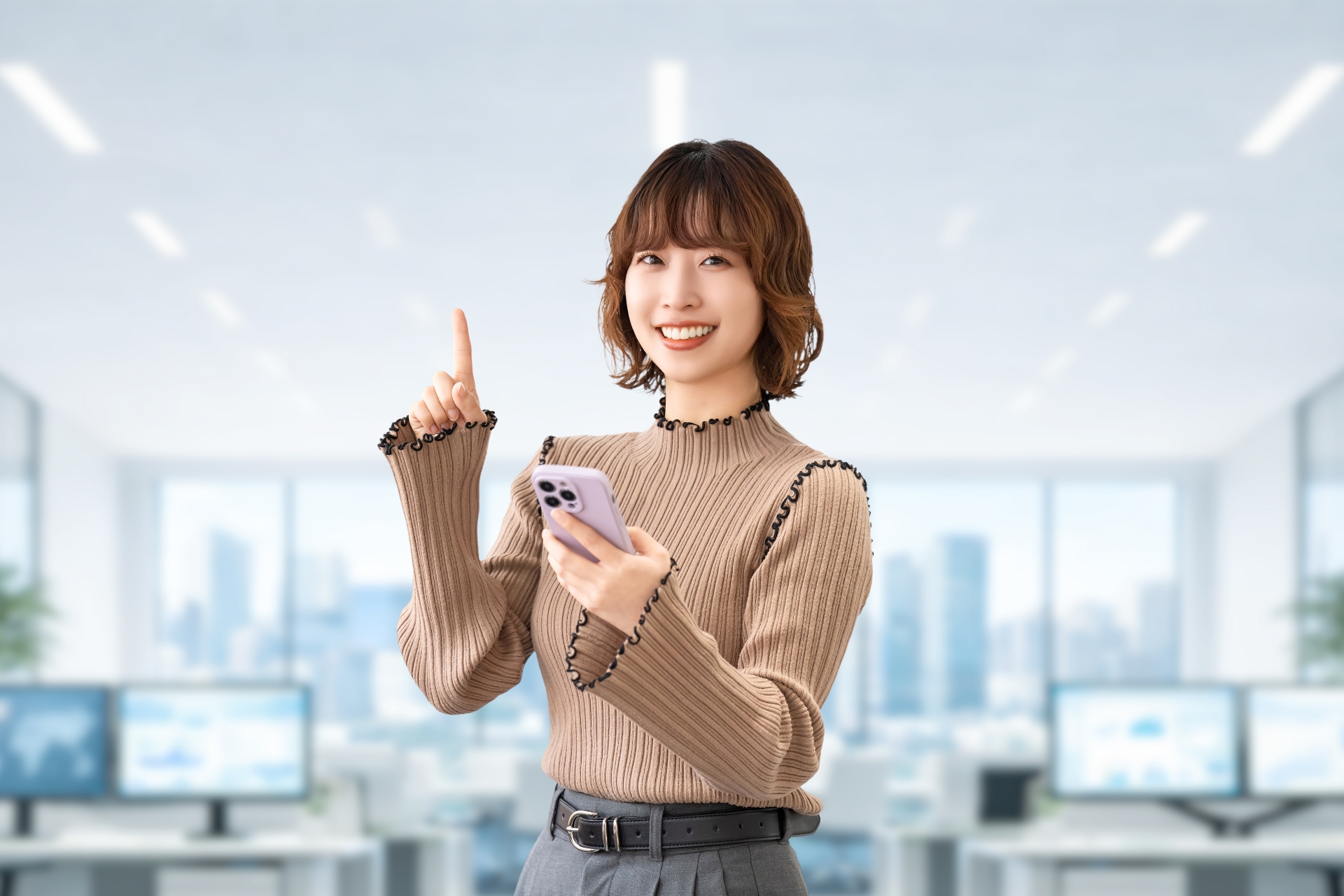 スマホを持って指を立てる笑顔の女性