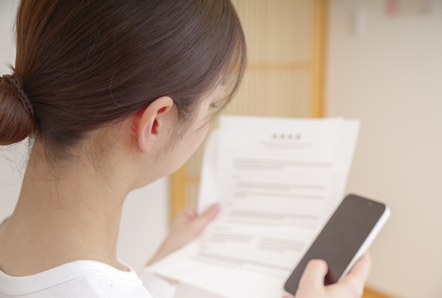 スマホと紙とにらめっこする女性