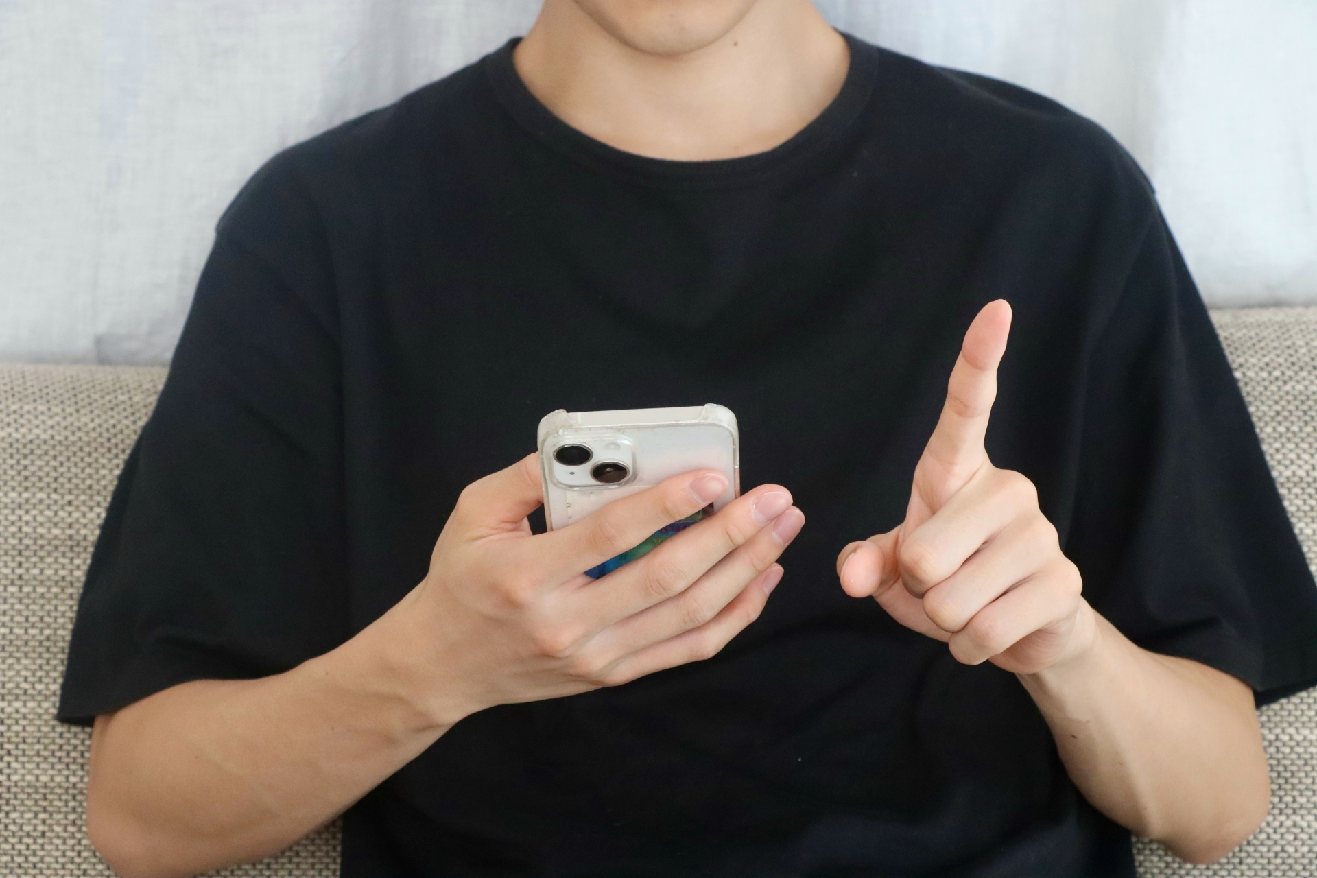 スマホを持って指を立てる人