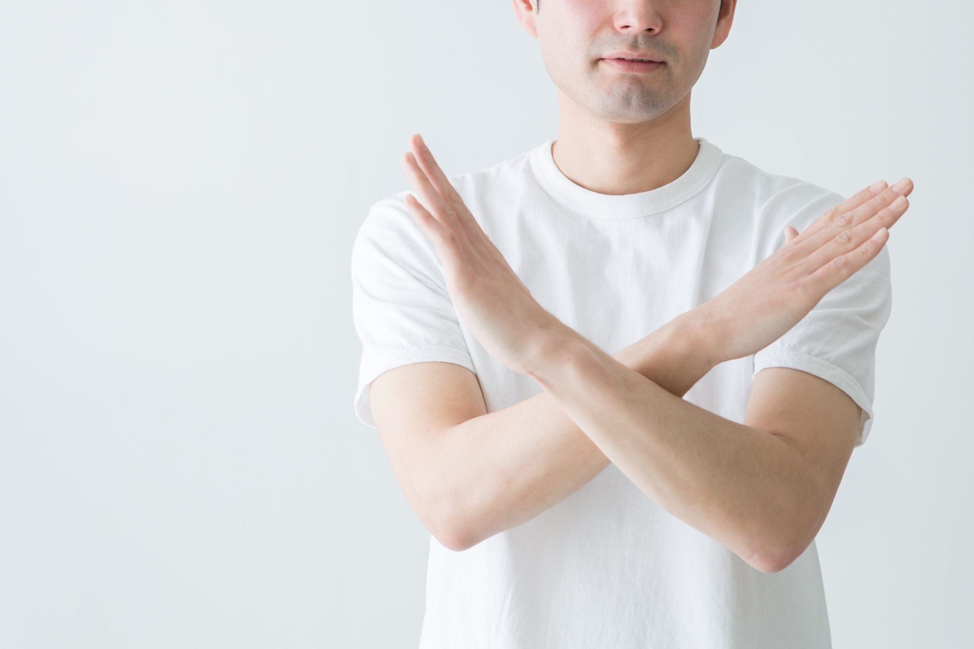 両手でバツマークをする男性