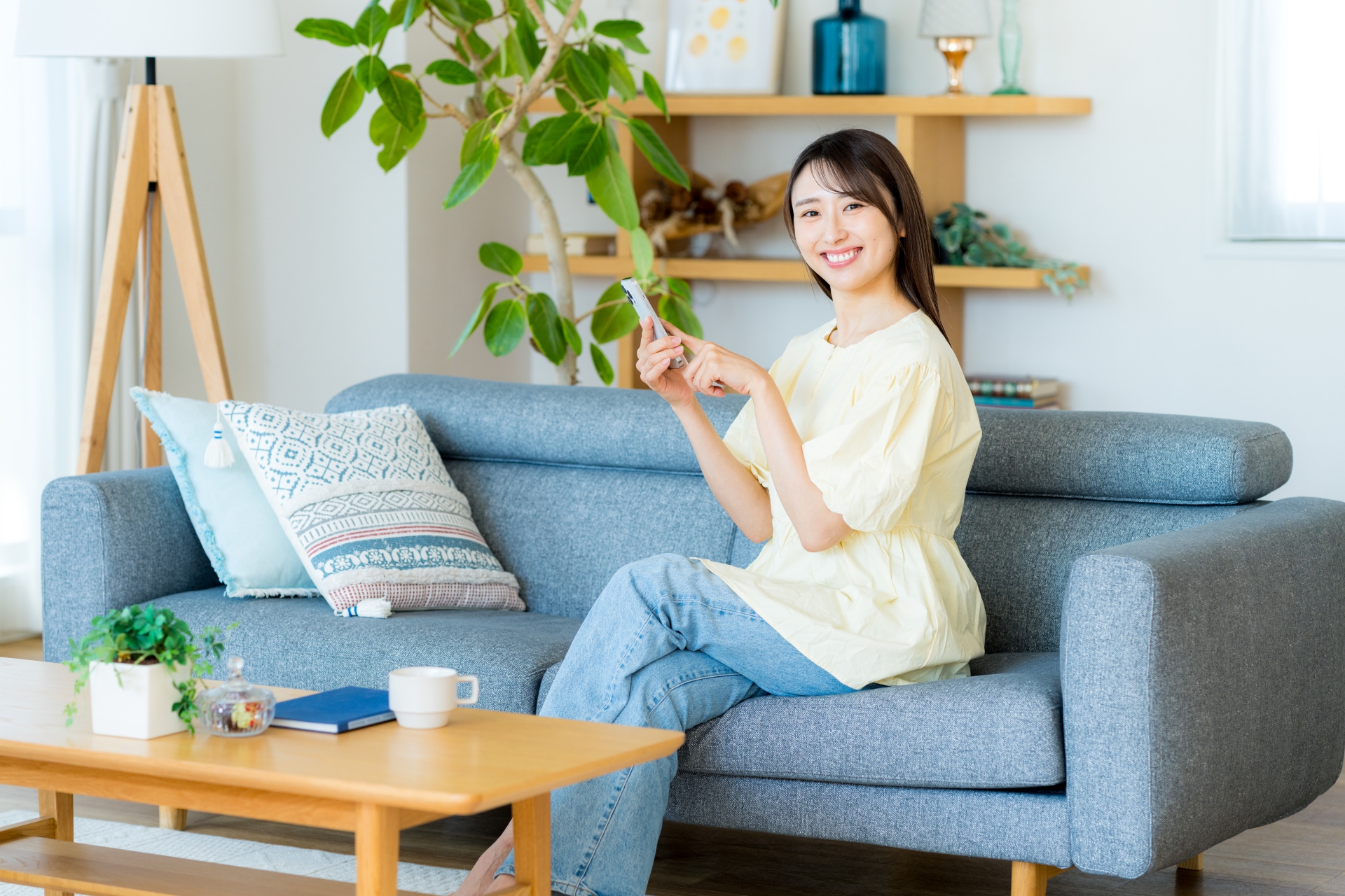部屋でスマホを操作する女性