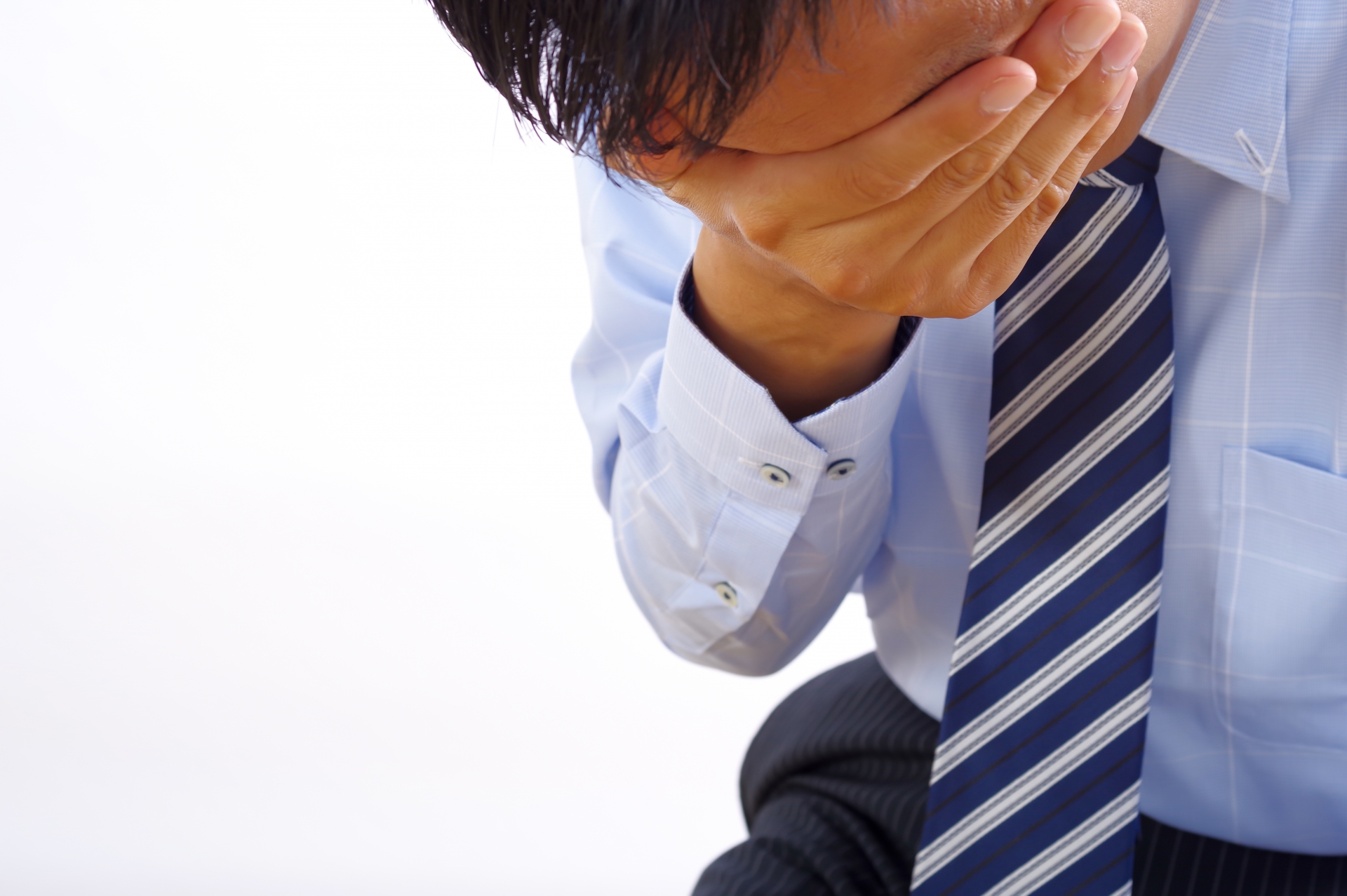 つらそうに頭を抱える男性ビジネスマン