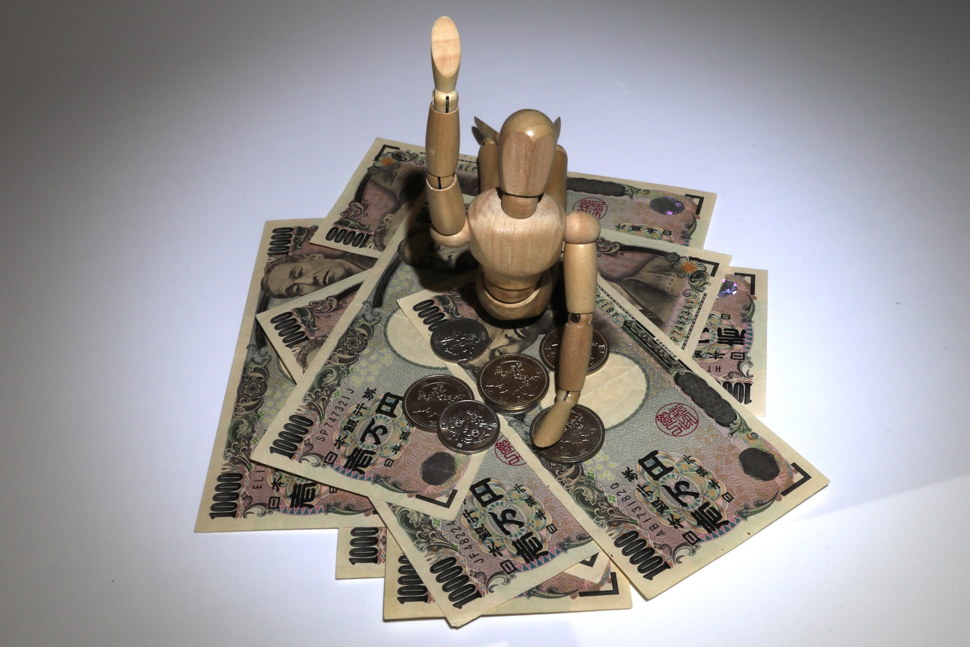 お金に埋もれる木製人形