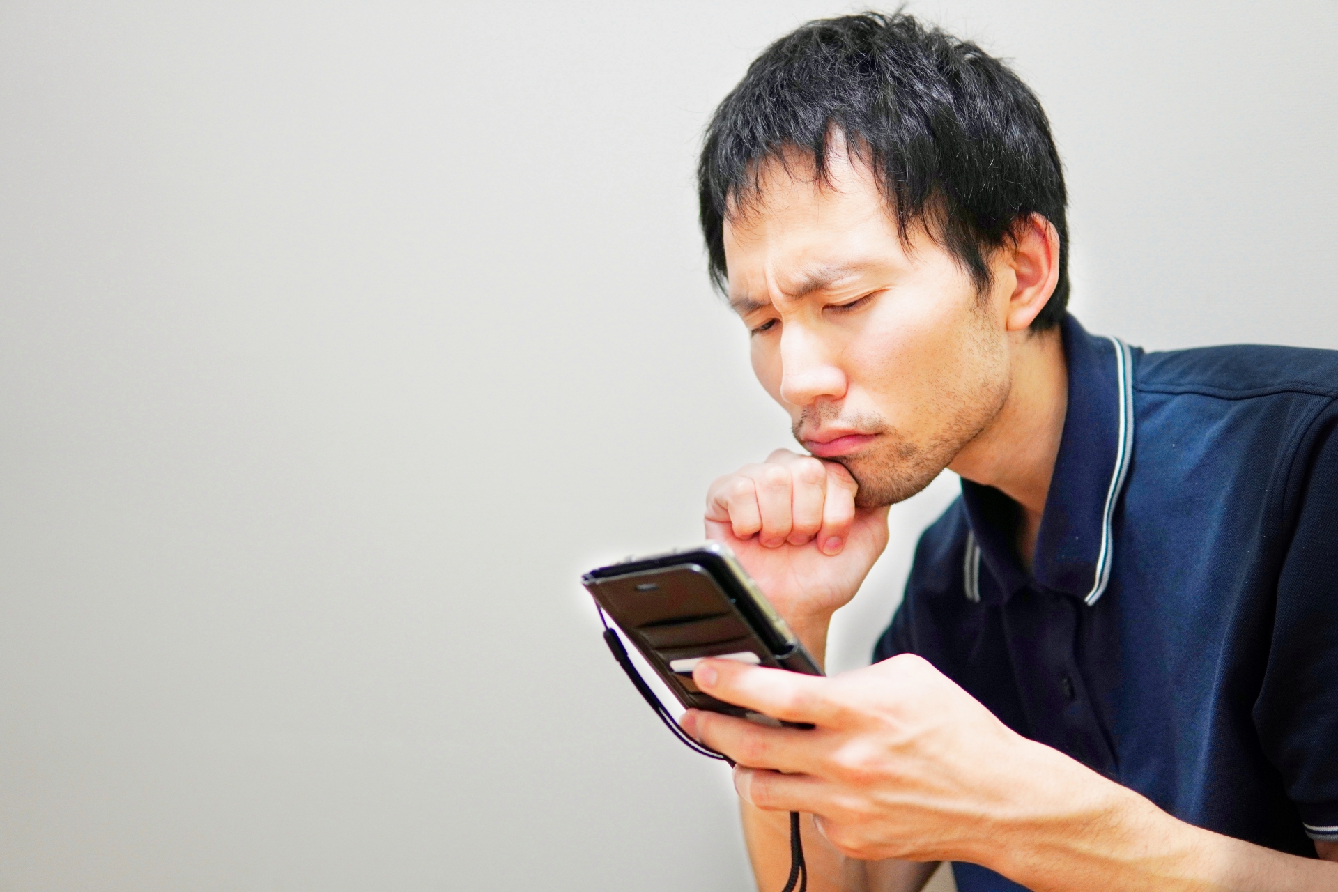 スマホを見て悩む男性