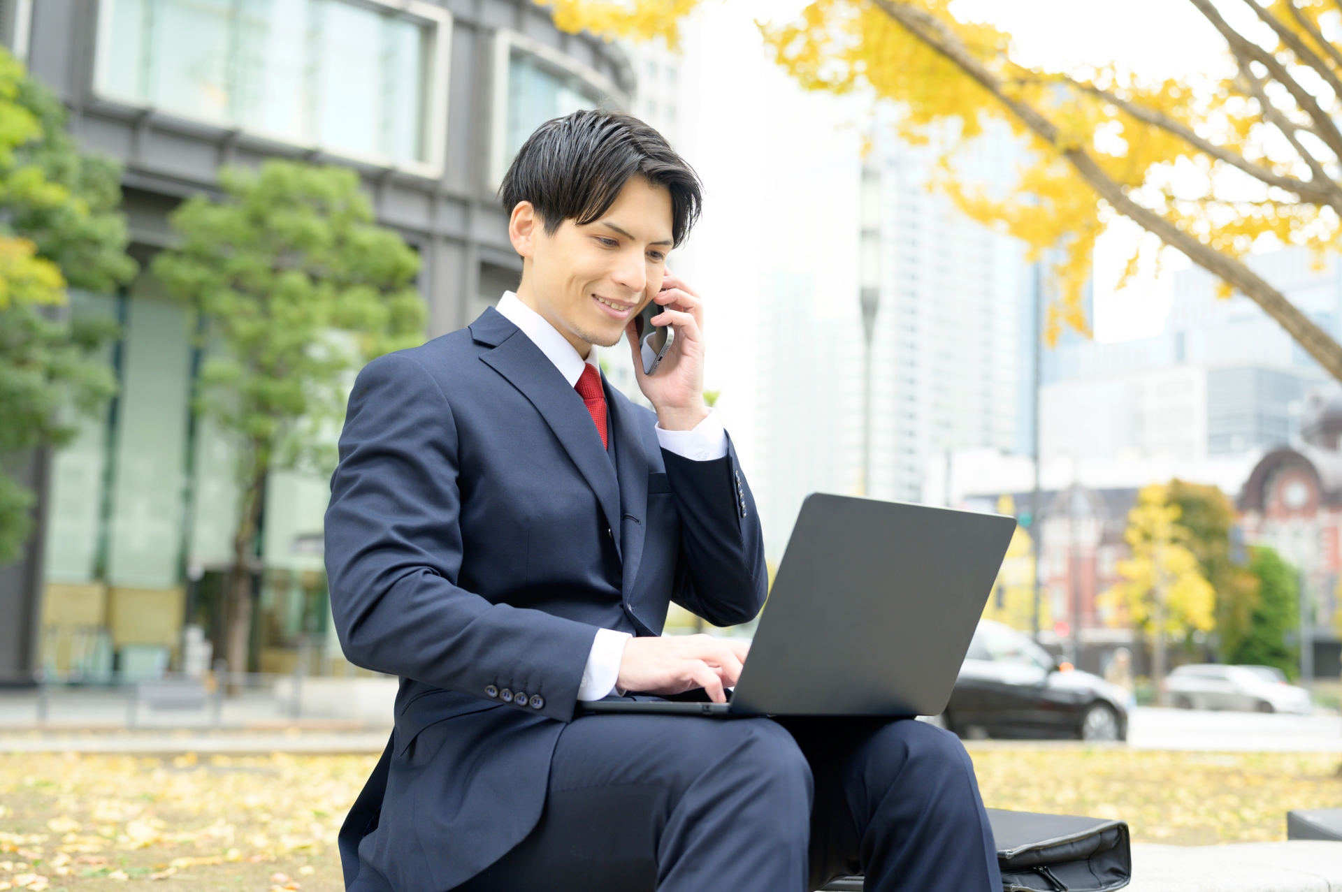 外で電話をしながらパソコンを操作する人