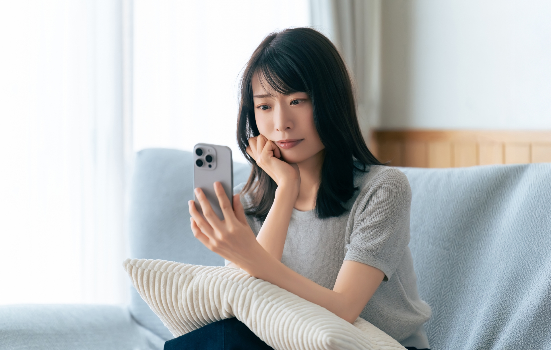 携帯電話を見て悩む女性