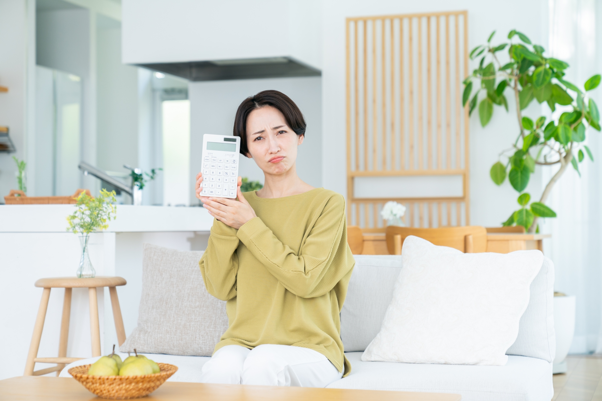 リビングで電卓を持つミドルの女性