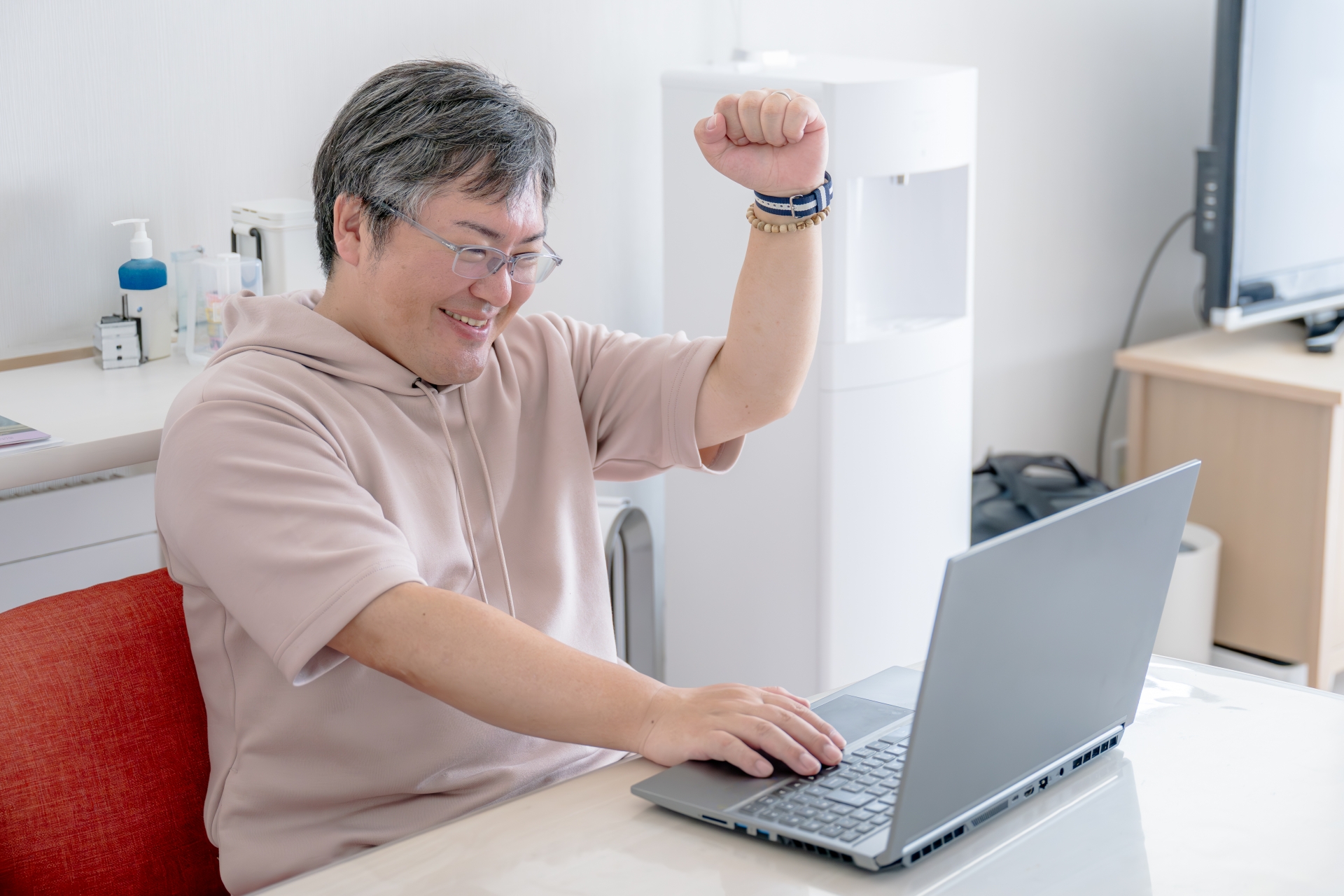 パソコンを見て笑顔でガッツポーズを作る男性