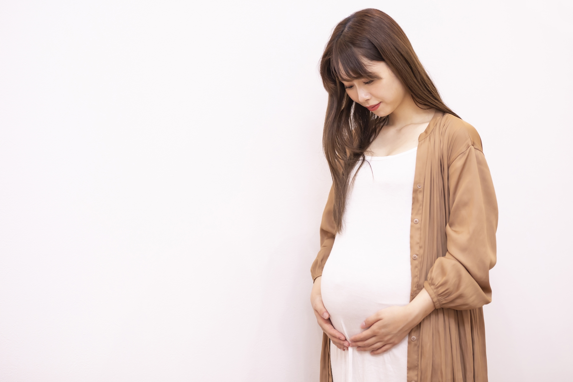 立ってお腹を眺める妊婦