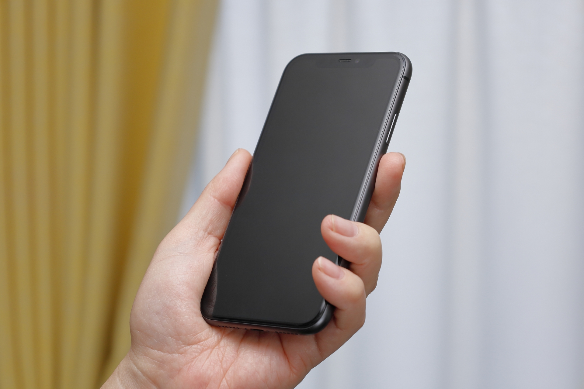 手にスマホを持つ