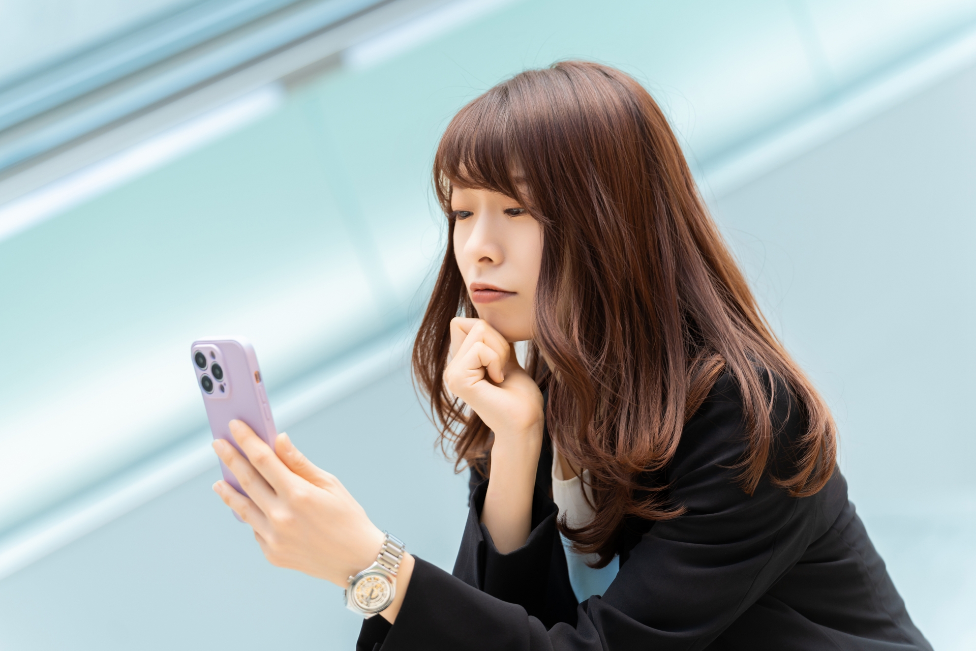 携帯電話を見て悩む女性
