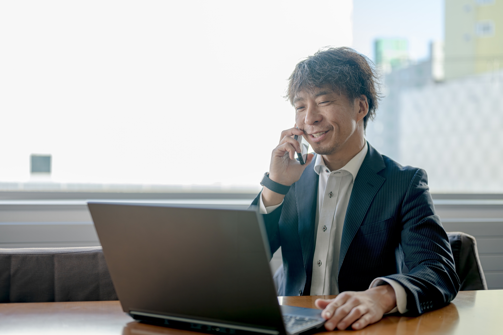 パソコンを見ながらスマホで通話する男性
