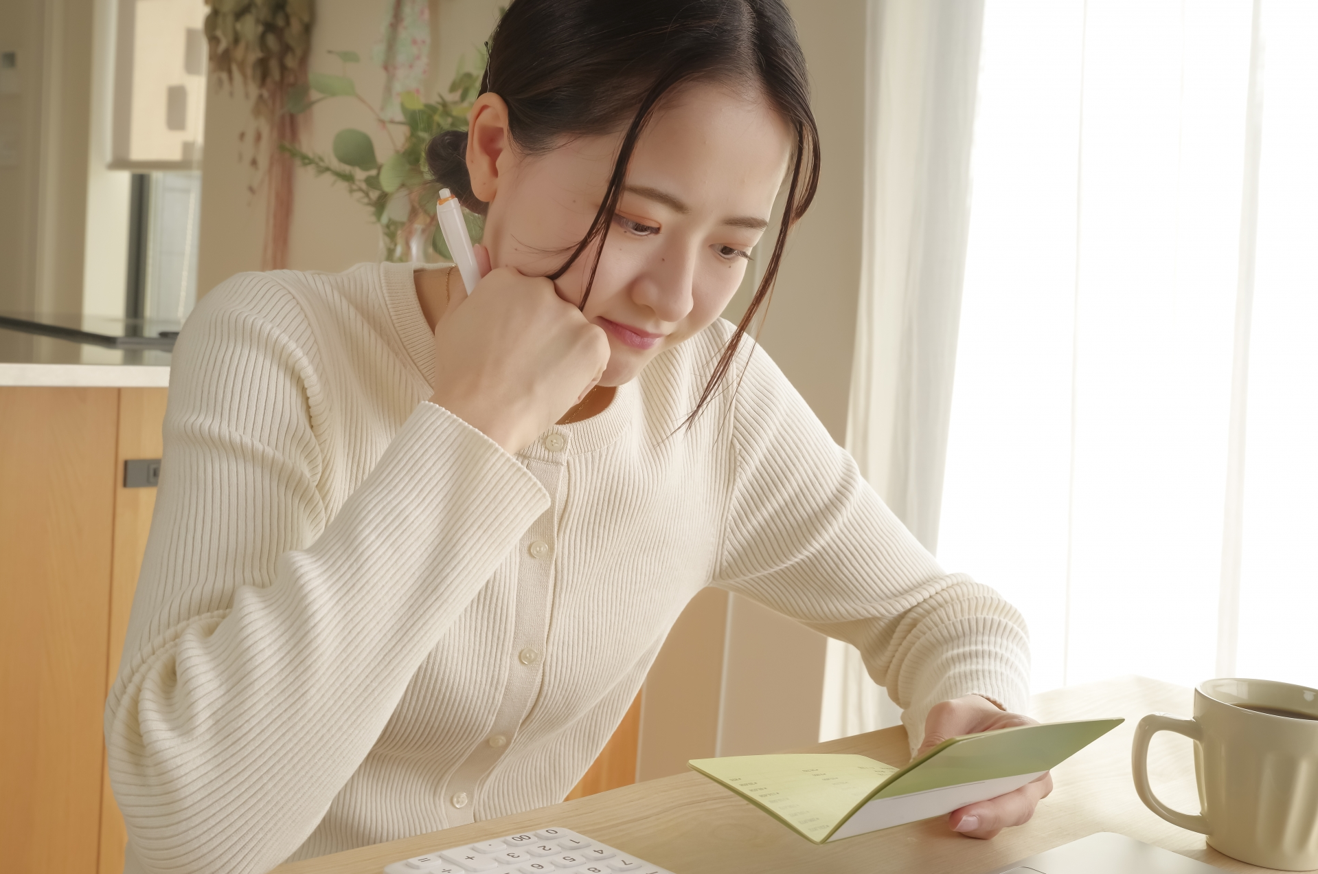 通帳を見て考え込む女性
